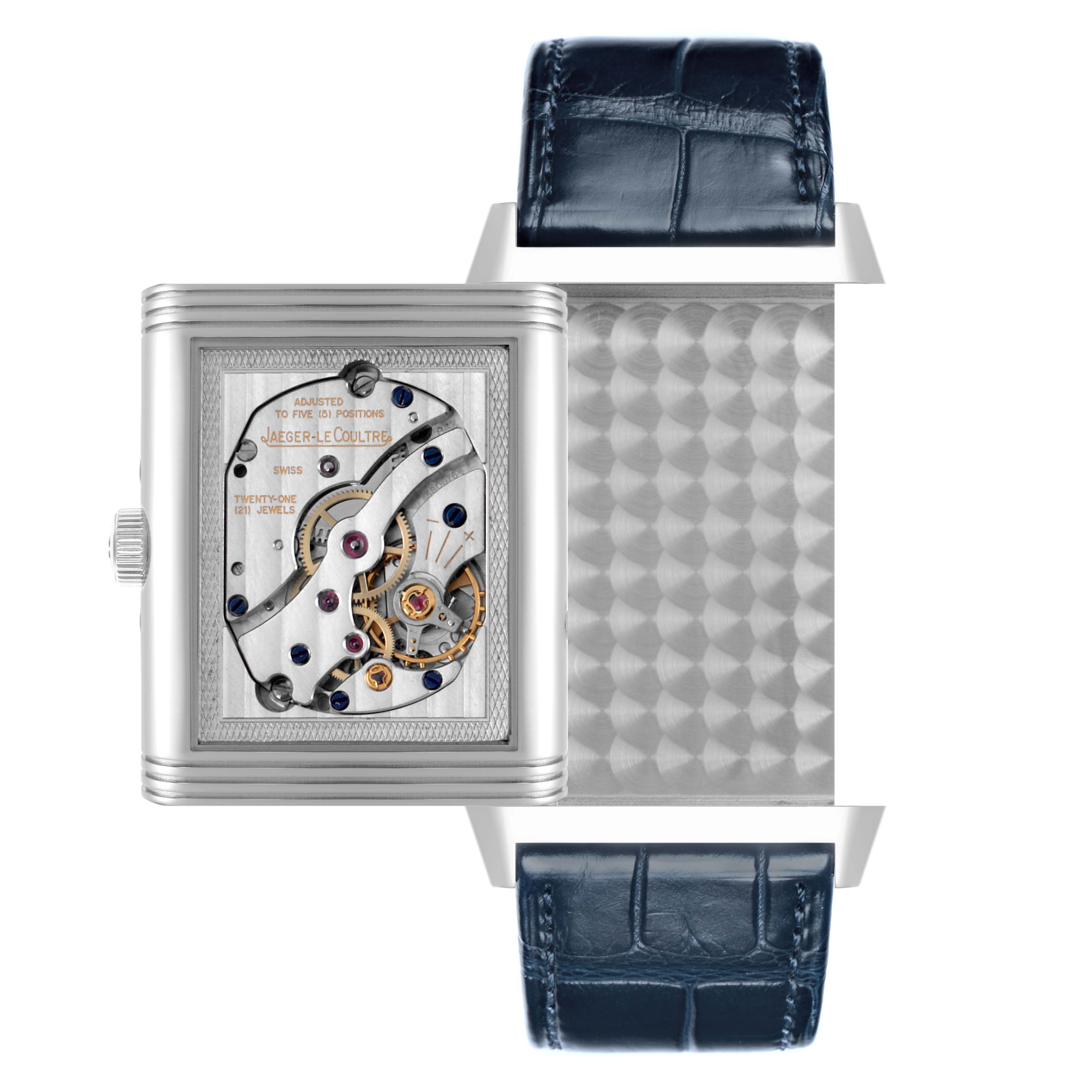 The Jaeger-LeCoultre Reverso watch is shown with its swiveling case open, revealing the mechanical movement and intricate gears.