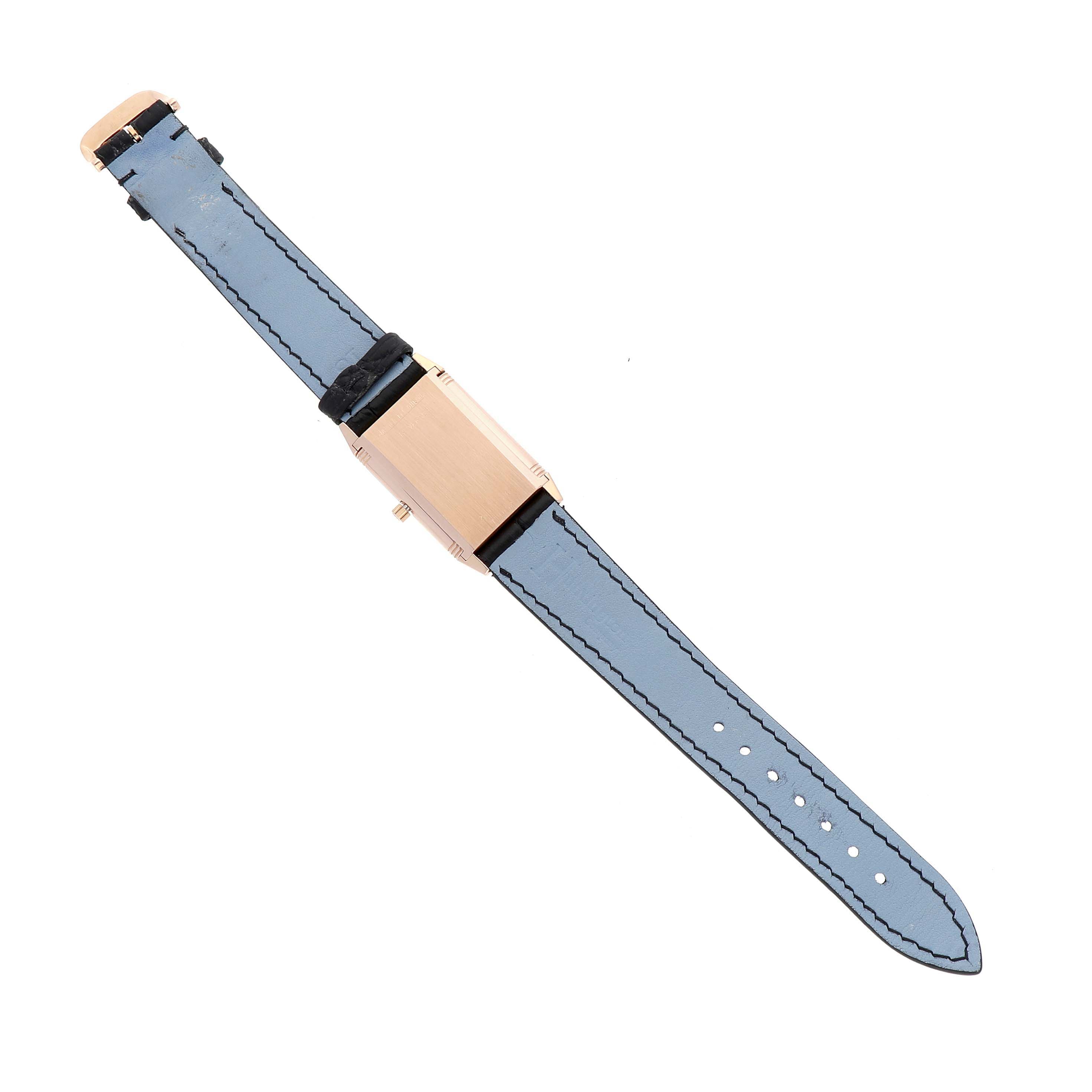 The Jaeger-LeCoultre Reverso watch is shown from above with its rectangular case and blue strap visible.