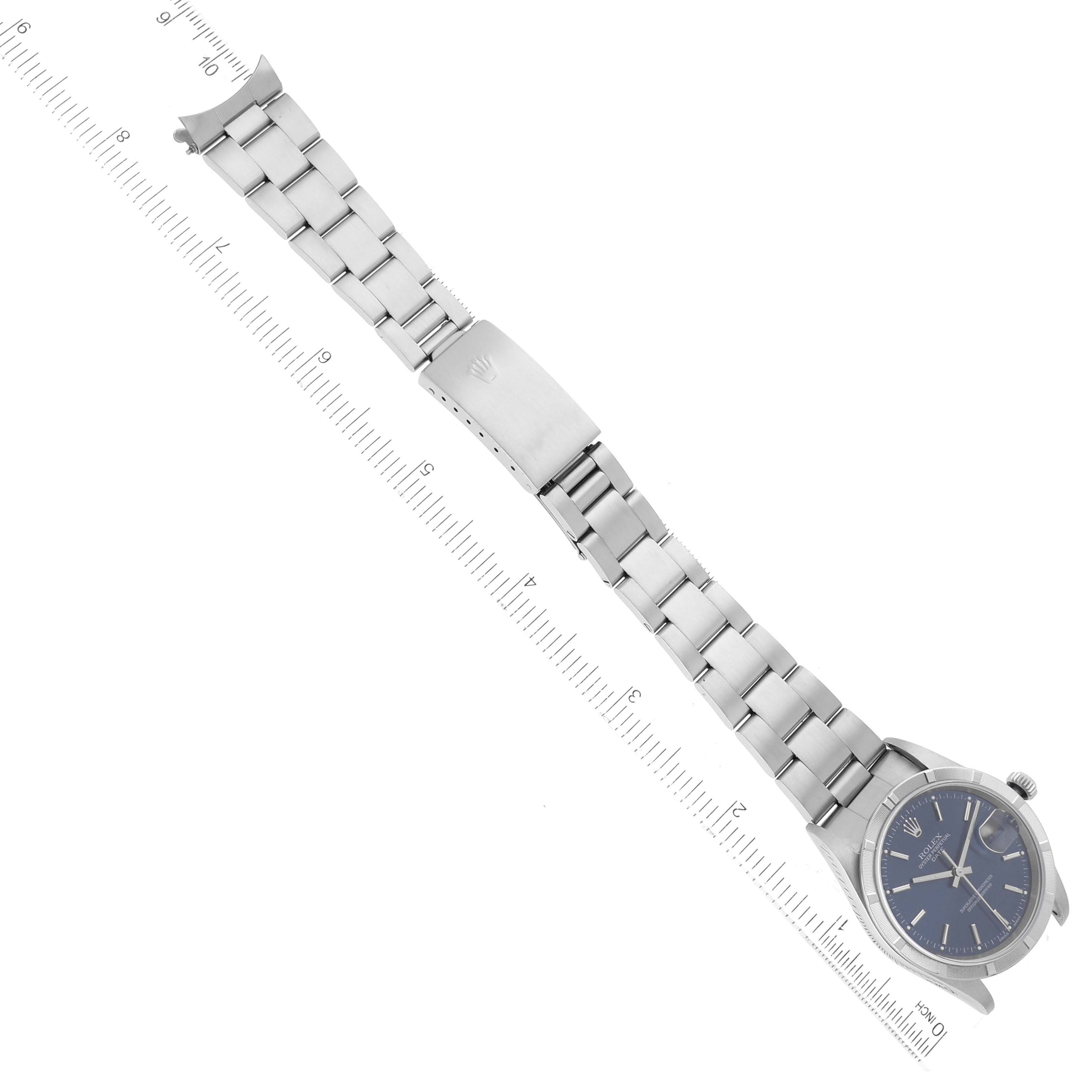 The image shows a Rolex Date 15210 Men's Stainless Steel Blue Dial 15210 Men's Stainless Steel Blue Dial model watch laid flat, displaying its face, bracelet, and clasp next to a ruler.