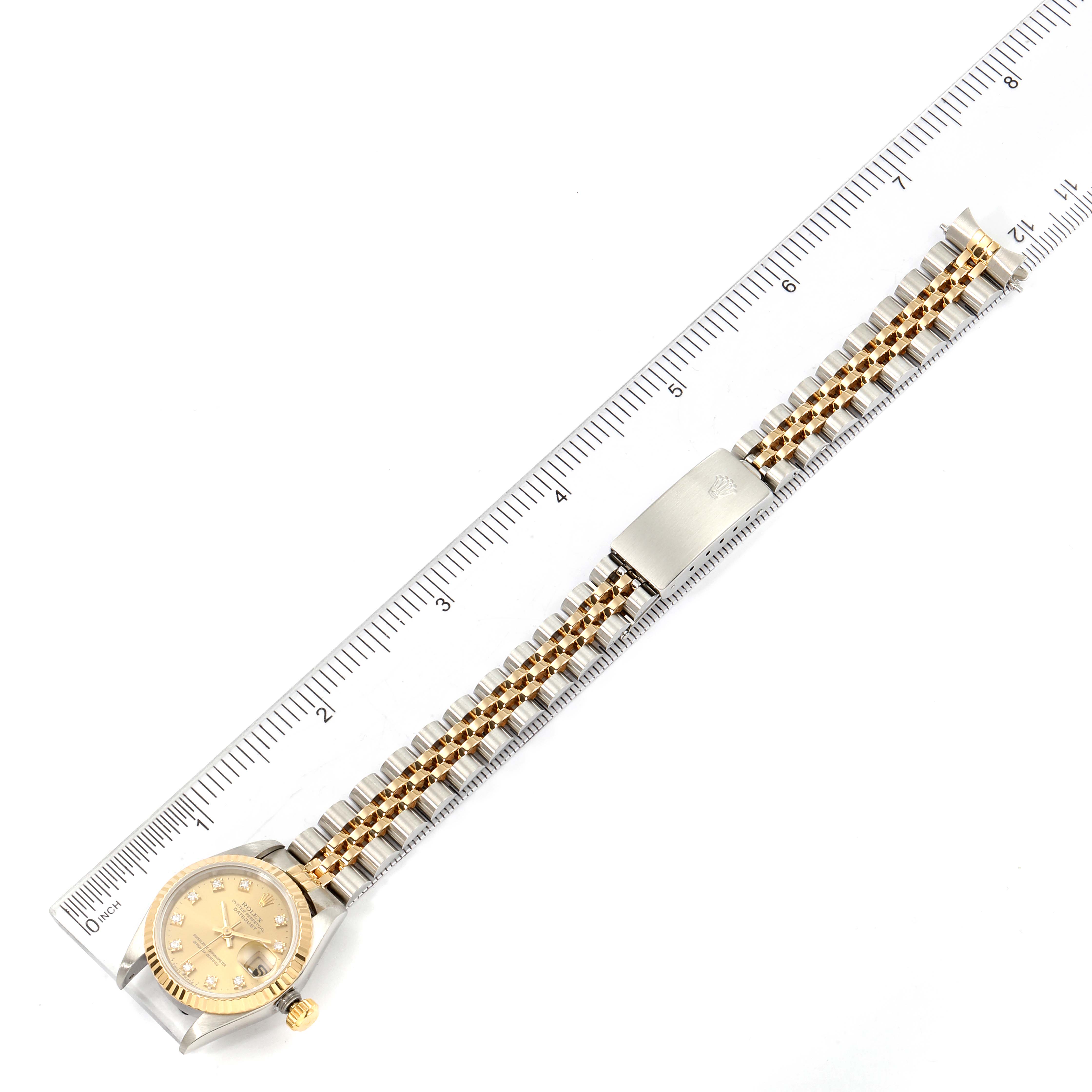 The image shows a top-down view of a Rolex Datejust 69173 Women's Steel and Gold (two tone) Champagne Dial 69173 Women's Steel and Gold (two tone) Champagne Dial watch with an integrated gold and silver bracelet, placed next to a ruler.