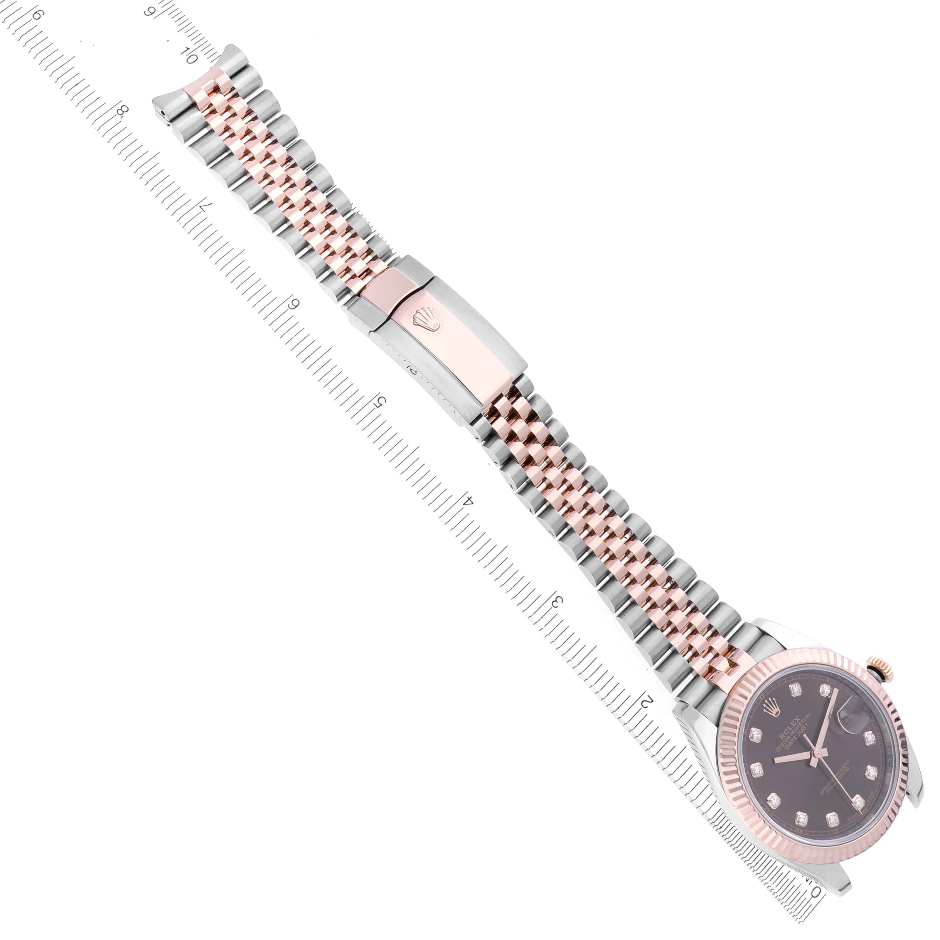 The Rolex Datejust 41 126331 Men
s Steel and Gold (two tone) Brown Dial 126331 Men
s Steel and Gold (two tone) Brown Dial is shown from a top-down angle, displaying the watch face, bracelet, and clasp with a ruler for scale.