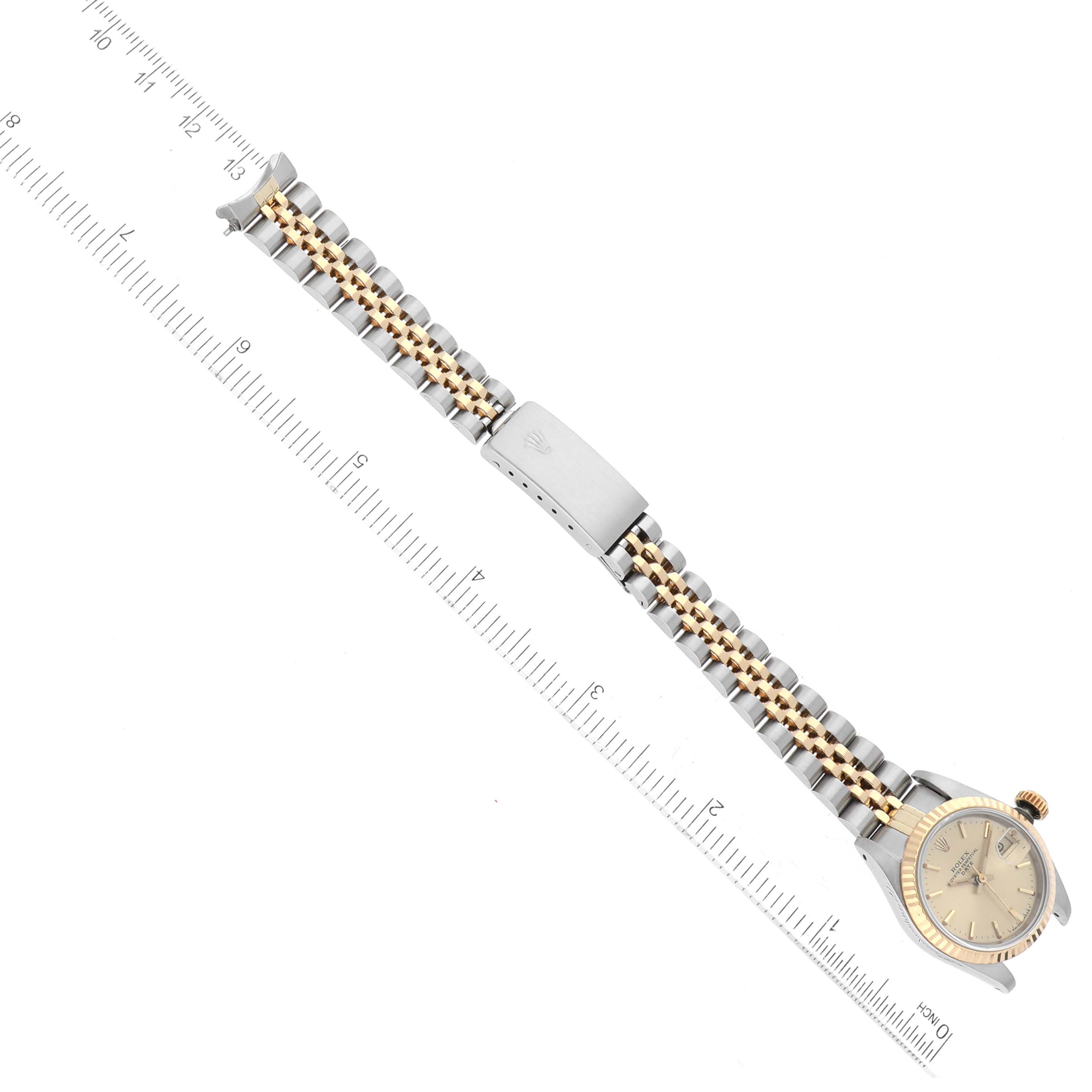 The image shows a top-down view of a Rolex Datejust 69173 Women's Steel and Gold (two tone) Champagne Dial 69173 Women's Steel and Gold (two tone) Champagne Dial watch, highlighting the dial, bracelet, and clasp alongside a measuring scale.