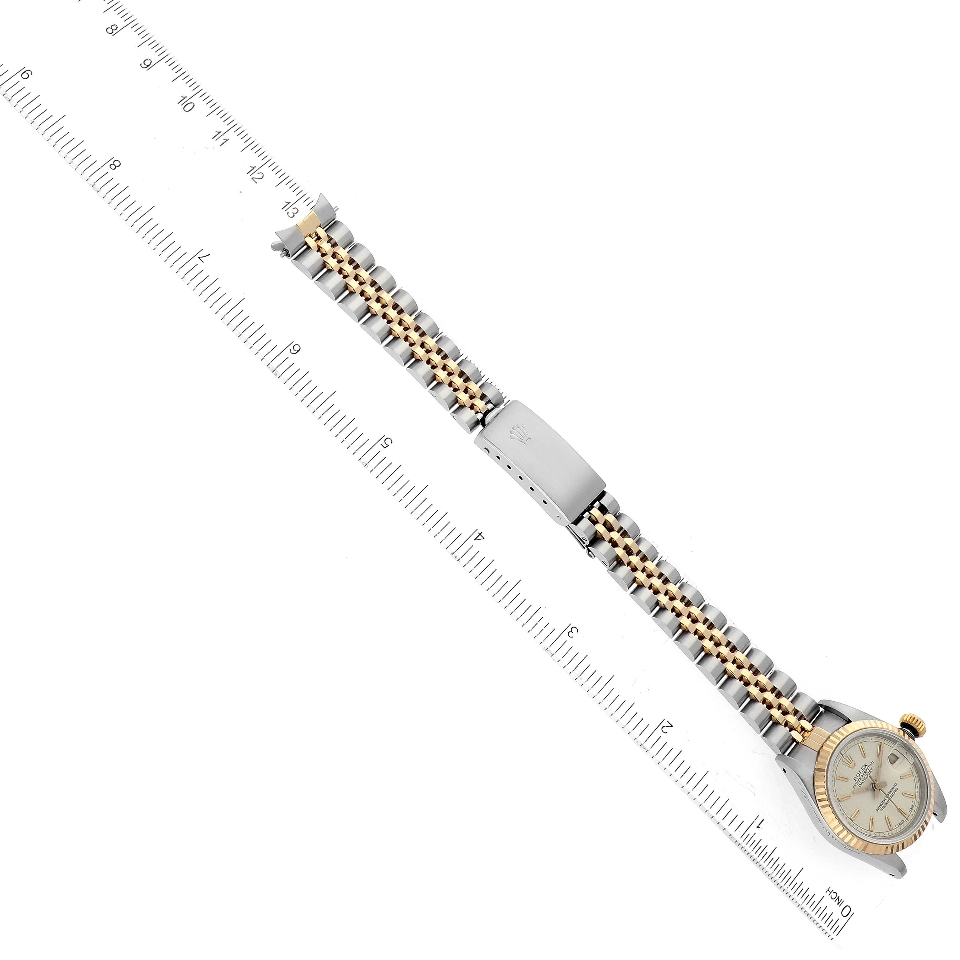 The image shows a top-down view of a Rolex Datejust 69173 Women's Steel and Gold (two tone) White Dial 69173 Women's Steel and Gold (two tone) White Dial watch with its gold and silver bracelet fully extended next to a ruler.