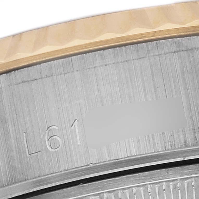 This close-up image of a Rolex Datejust 69173 Women's Steel and Gold (two tone) White Dial 69173 Women's Steel and Gold (two tone) White Dial watch shows a portion of the fluted bezel and the engraved serial number on the case.
