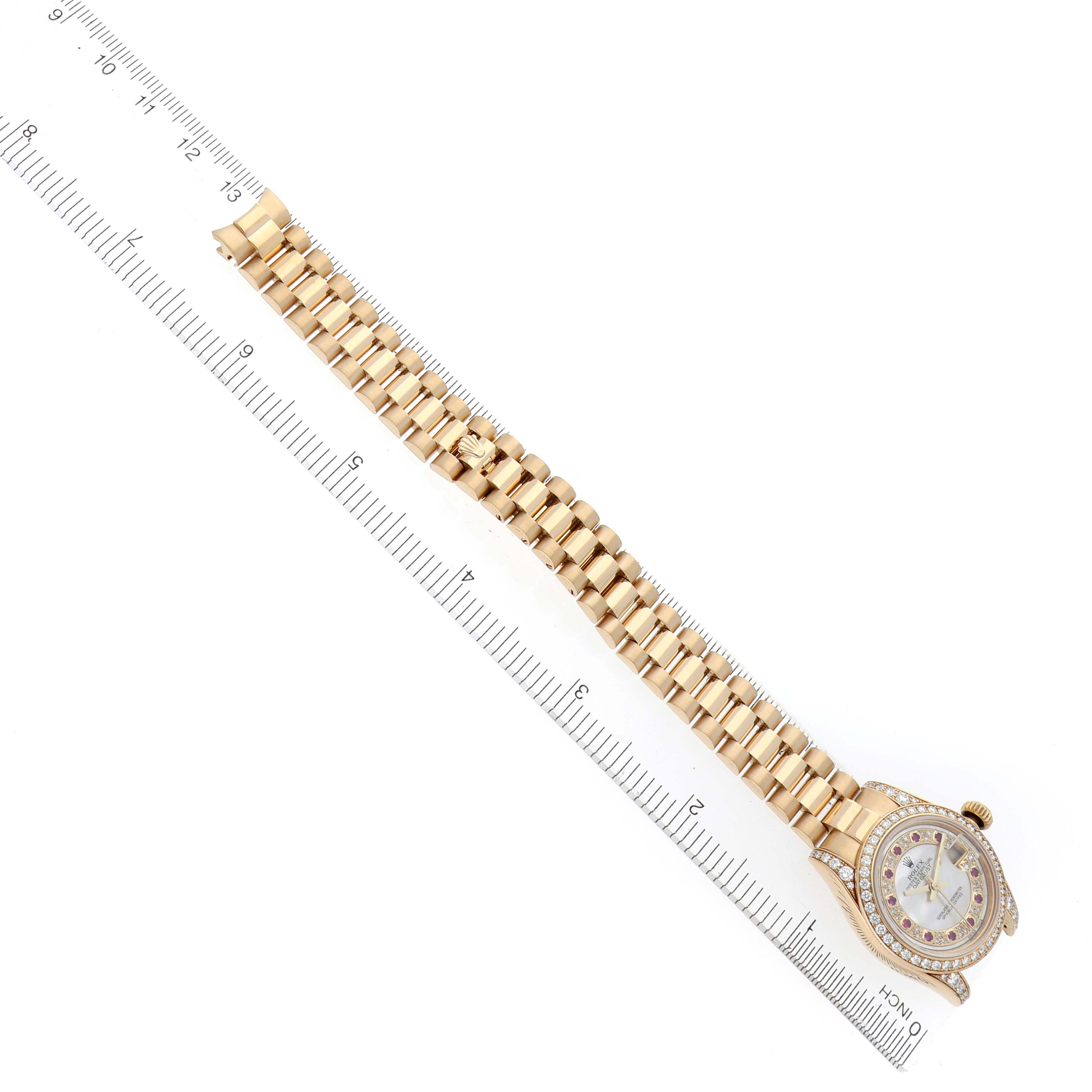 The Rolex President 179158 Women's Yellow Gold Mother of Pearl Dial 179158 Women's Yellow Gold Mother of Pearl Dial watch is shown from a top view, showcasing the full bracelet and face, alongside a ruler for scale.