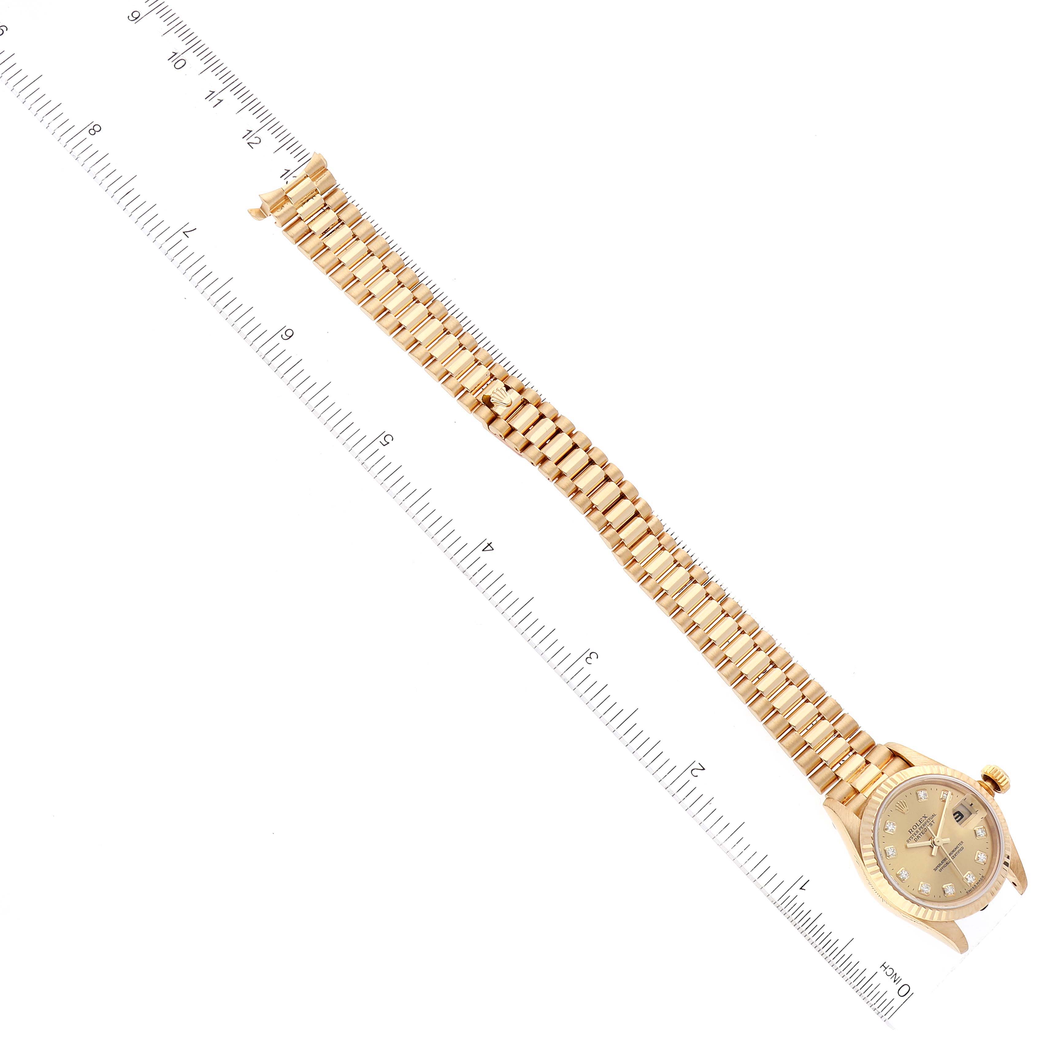 The image shows a Rolex President 79178 Women
s Yellow Gold Champagne Dial 79178 Women
s Yellow Gold Champagne Dial model watch from a top-down angle, displaying the face, bracelet, and a ruler for scale.