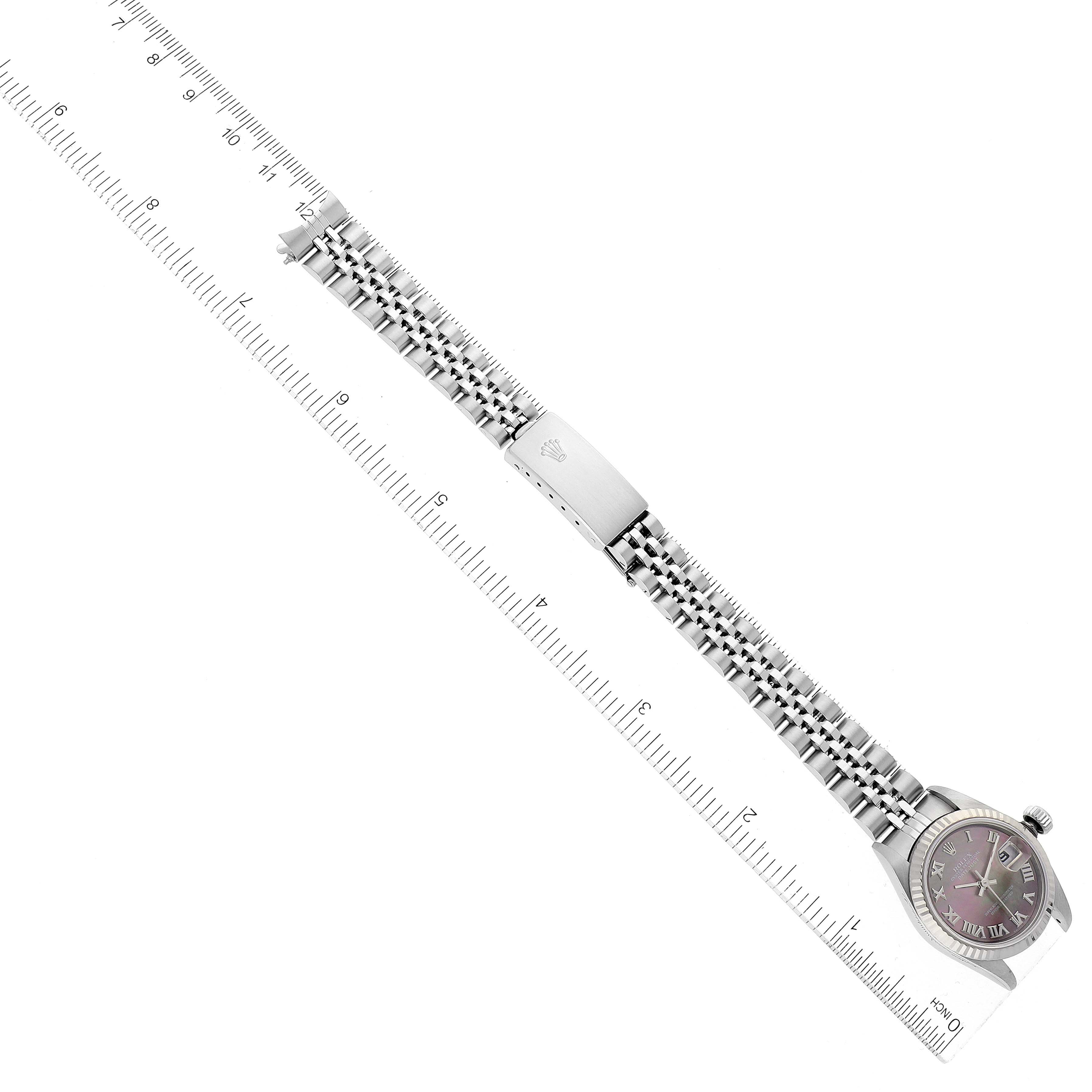 This is an overhead view of a Rolex Datejust 79174 Women's Stainless Steel Mother of Pearl Dial 79174 Women's Stainless Steel Mother of Pearl Dial watch with the full bracelet extended alongside a ruler.