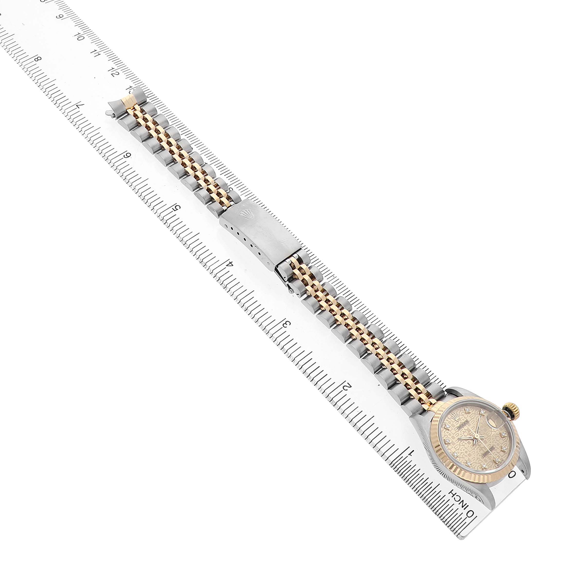 The Rolex Datejust 69173 Women's Steel and Gold (two tone) Champagne Dial watch is shown from an angled top view, highlighting the face, bezel, bracelet, and clasp on a ruler.