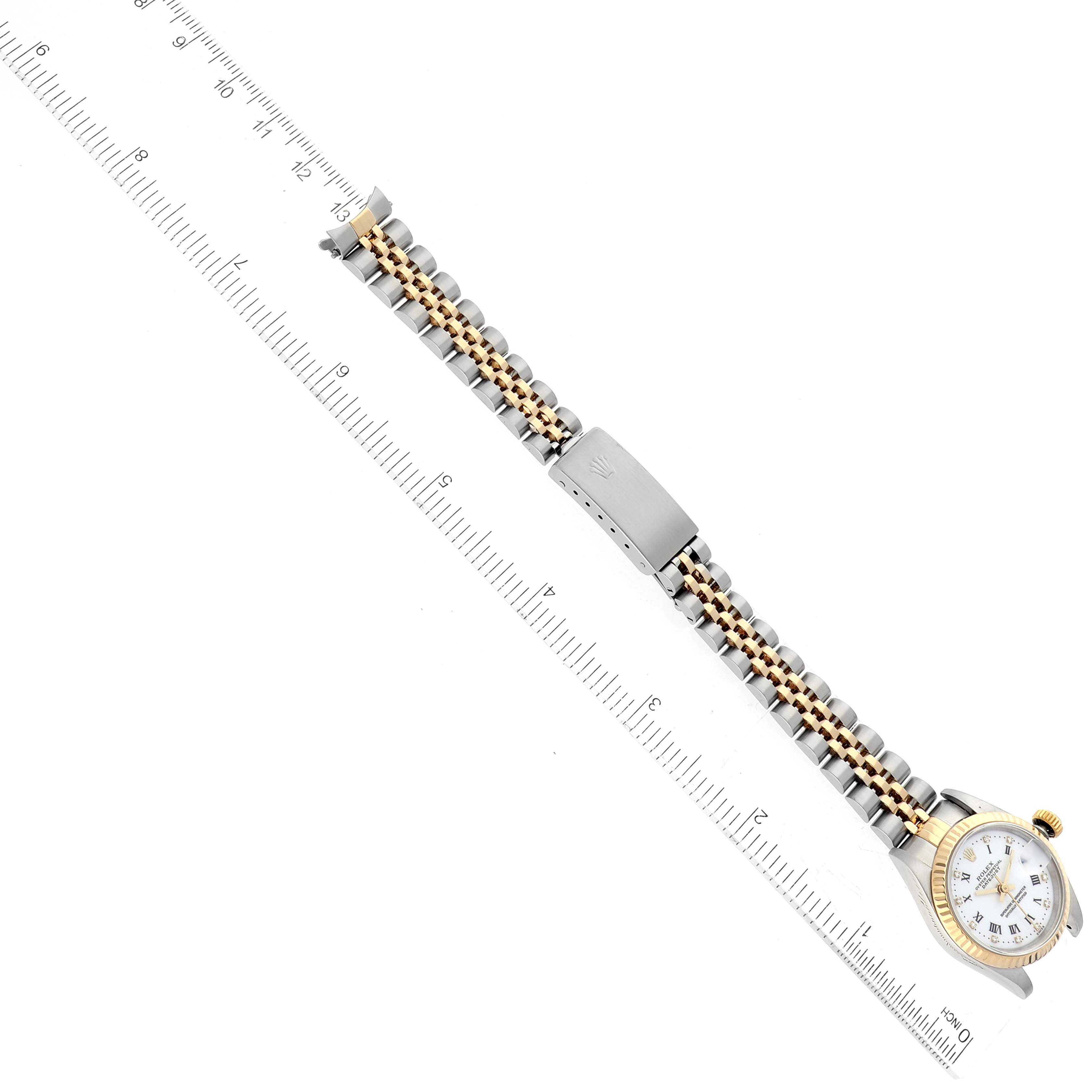 The image shows a top-down view of a Rolex Datejust 69173G Women's Steel and Gold (two tone) White Dial 69173G Women's Steel and Gold (two tone) White Dial watch with its full strap extended next to a ruler.
