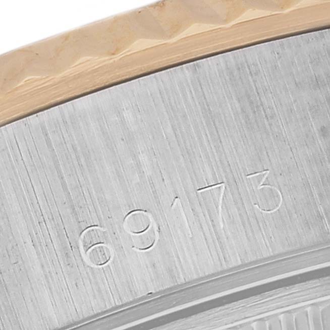 This close-up image of a Rolex Datejust 69173 Women's Steel and Gold (two tone) White Dial 69173 Women's Steel and Gold (two tone) White Dial model watch shows the bezel and part of the watch's engraved serial number.