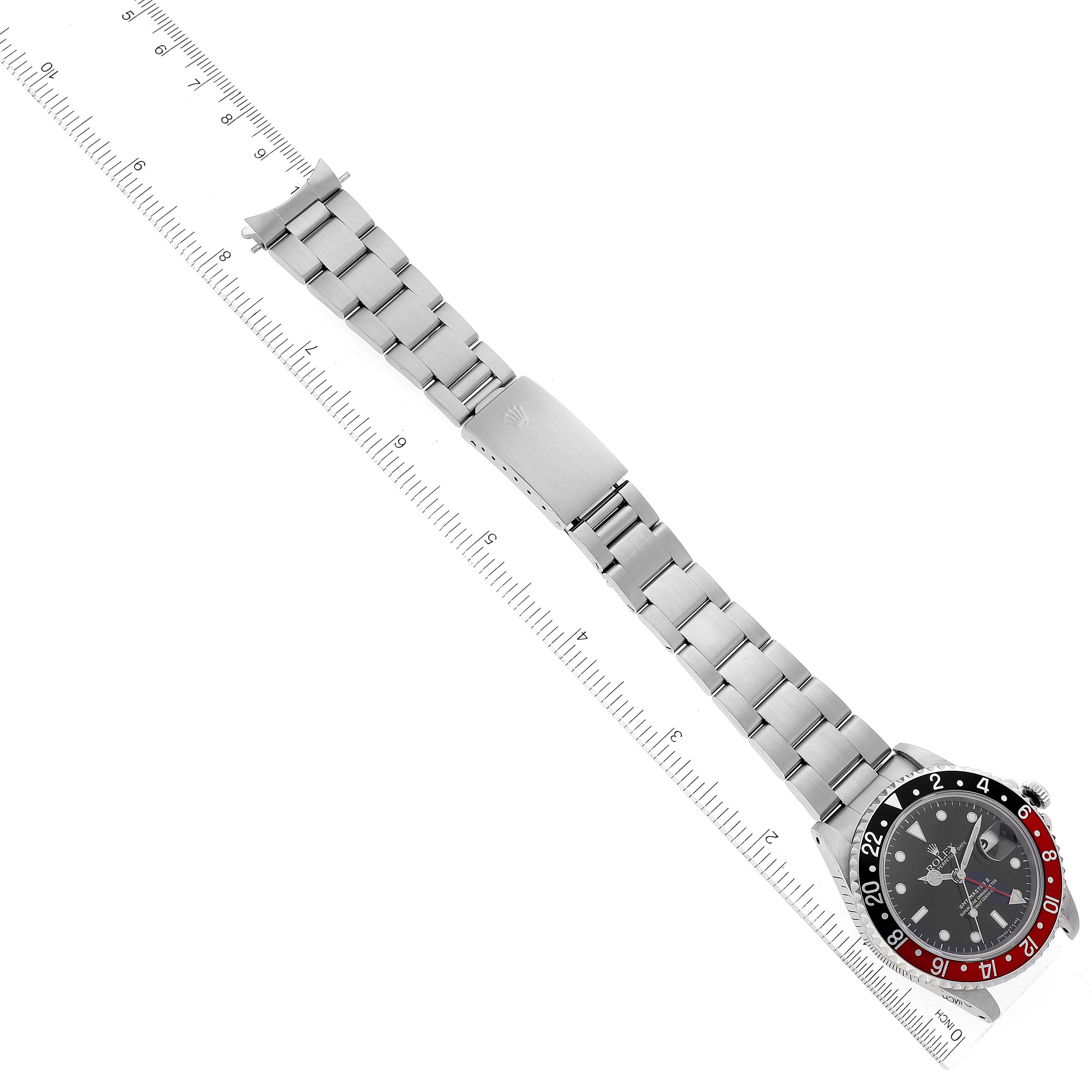 This image shows a top-down view of a Rolex GMT-Master 16710 Men
s Stainless Steel Black Dial 16710 Men
s Stainless Steel Black Dial watch, including its bezel, dial, and metal bracelet next to a ruler.