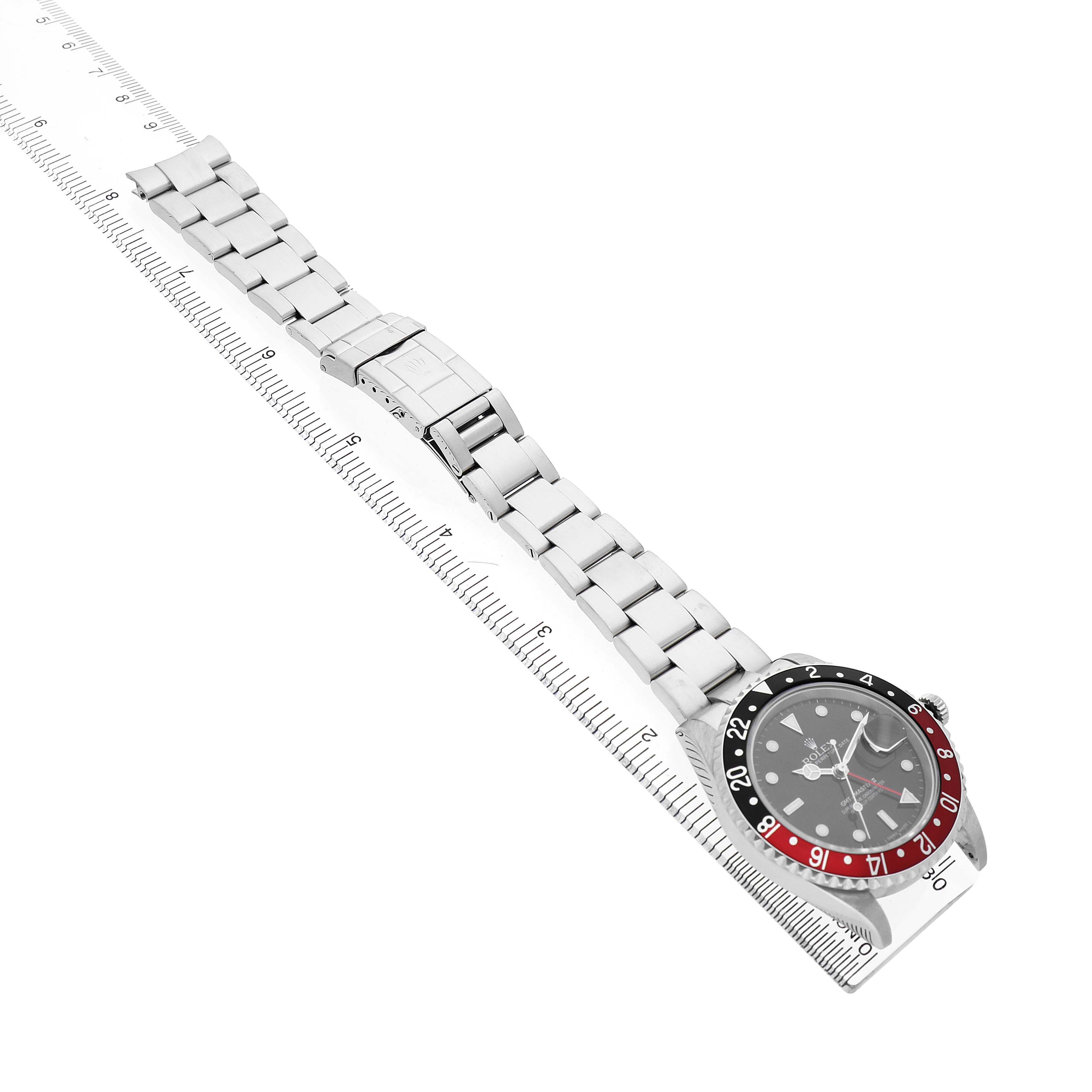 The Rolex GMT-Master 16710 Men's Stainless Steel Black Dial is shown at a diagonal angle, displaying the face, bezel, and metal bracelet alongside a ruler for scale.