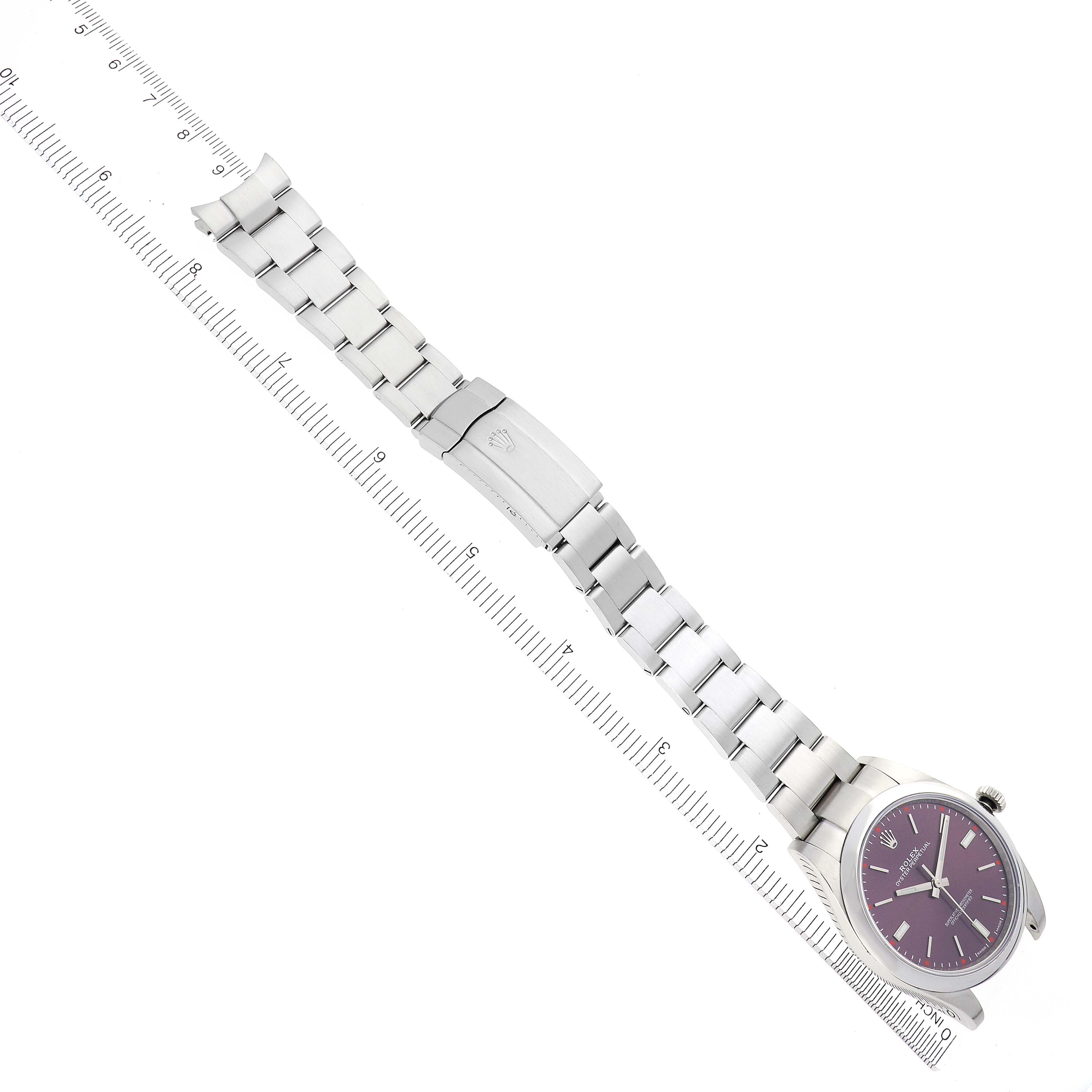 The Rolex Oyster Perpetual 114300 Men's Stainless Steel Purple Dial 114300 Men's Stainless Steel Purple Dial watch is shown from a top-down angle, displaying its full bracelet and clasp alongside a ruler.