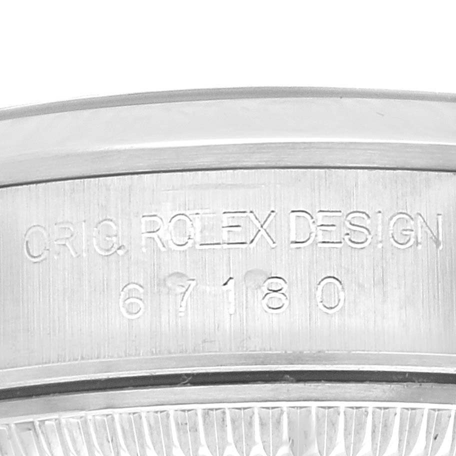 The image shows an up-close view of the engraved model number and design on the case of a Rolex Oyster Perpetual 67180 Women's Stainless Steel Blue Dial 67180 Women's Stainless Steel Blue Dial watch.