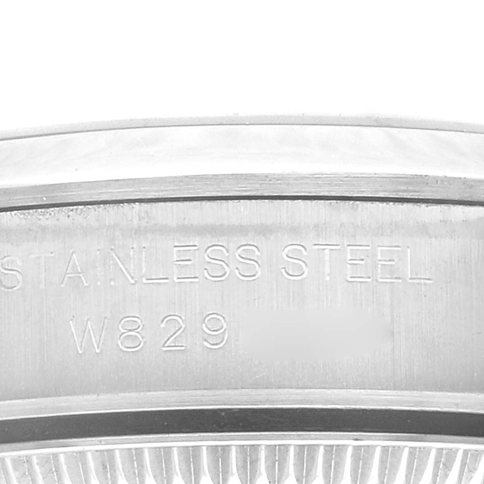 The image shows a close-up of the side of a Rolex Oyster Perpetual 67180 Women's Stainless Steel Pink Dial 67180 Women's Stainless Steel Pink Dial watch, highlighting the engraved text "STAINLESS STEEL" and a serial number.