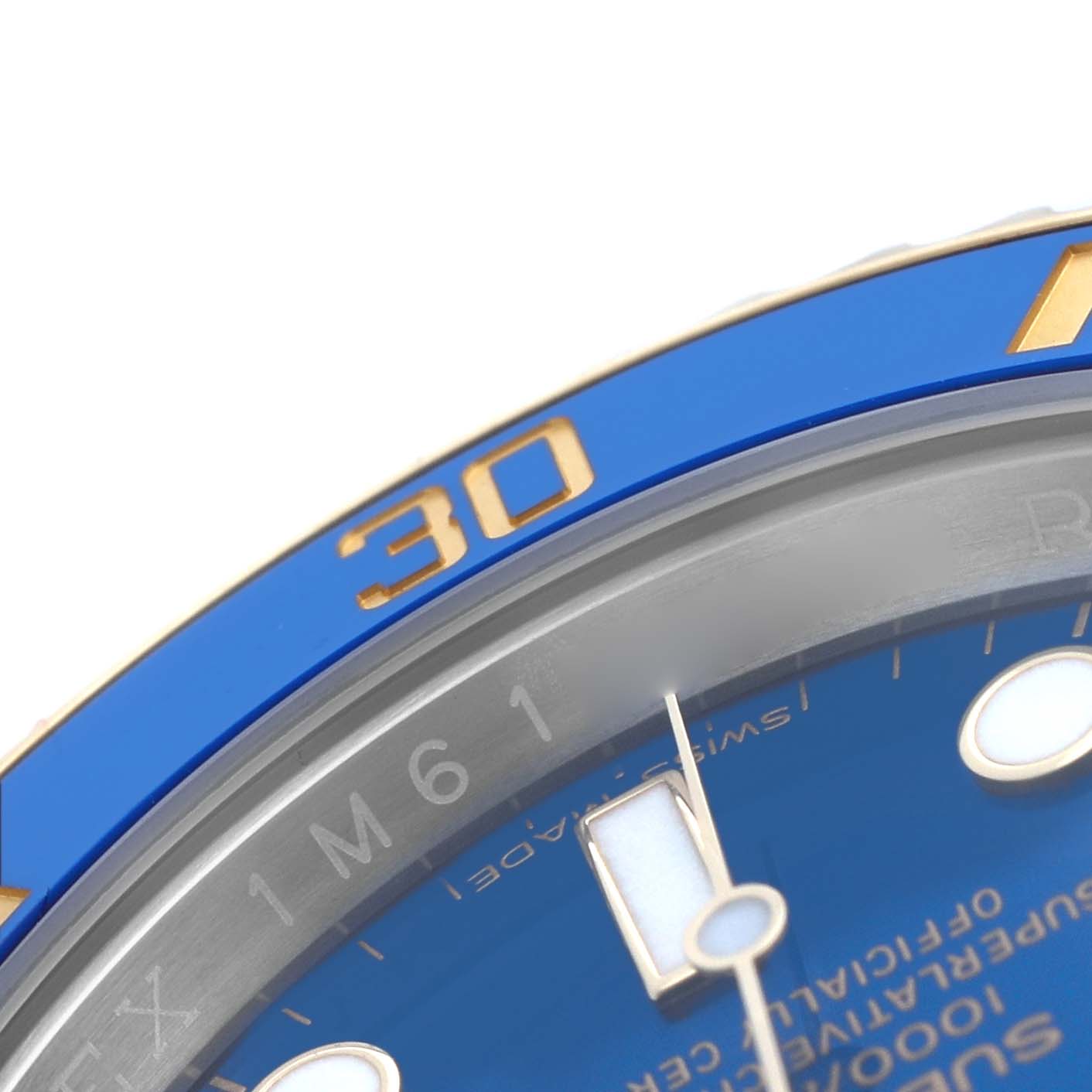 The image shows a close-up of the Rolex Submariner 116613 Men's Steel and Gold (two tone) Blue Dial's blue bezel, gold numerals, and part of the dial with a luminescent hand.