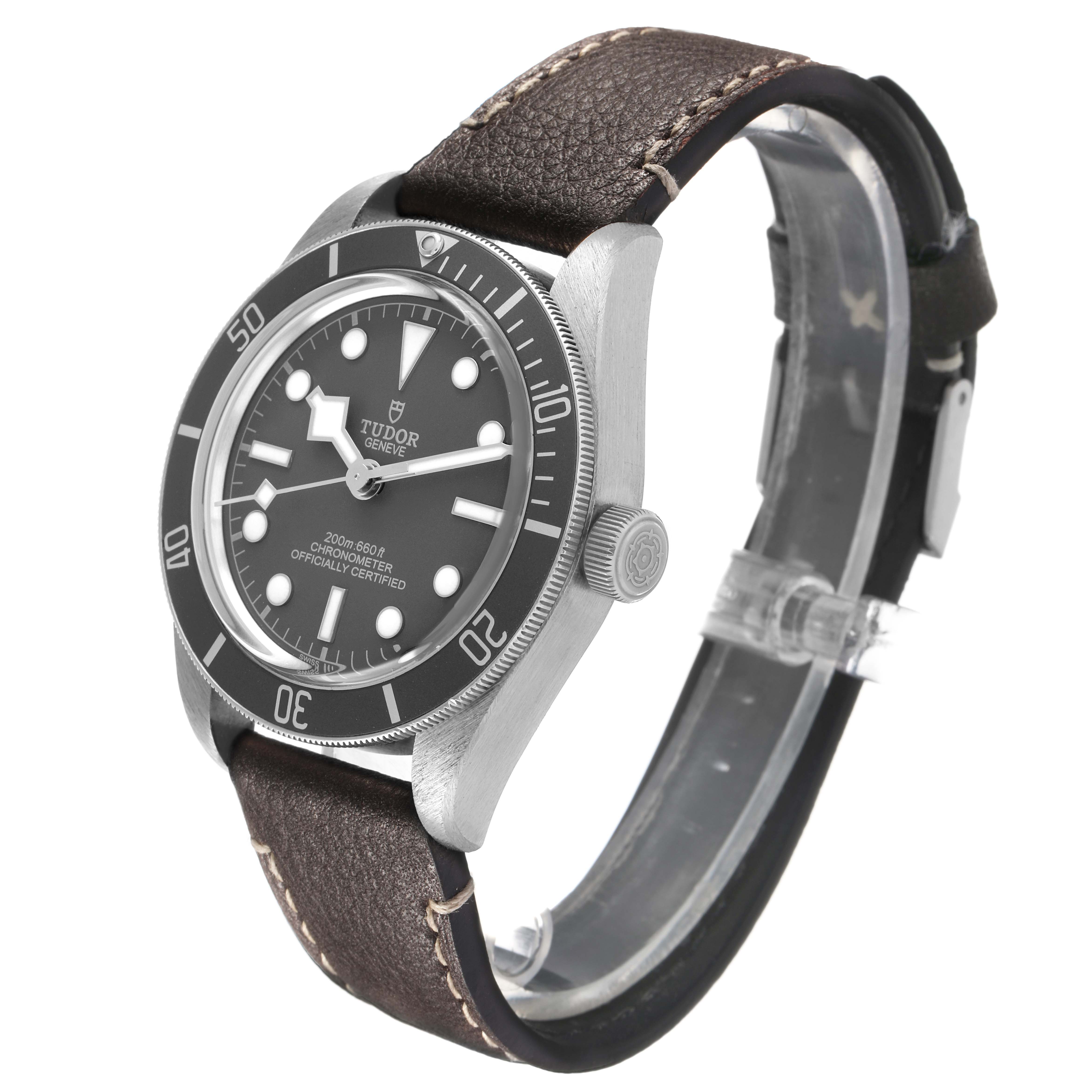 The Tudor Heritage Black Bay 79010 Men's Stainless Steel Grey Dial watch is shown at a three-quarter angle, displaying its dial, bezel, crown, case, and leather strap.