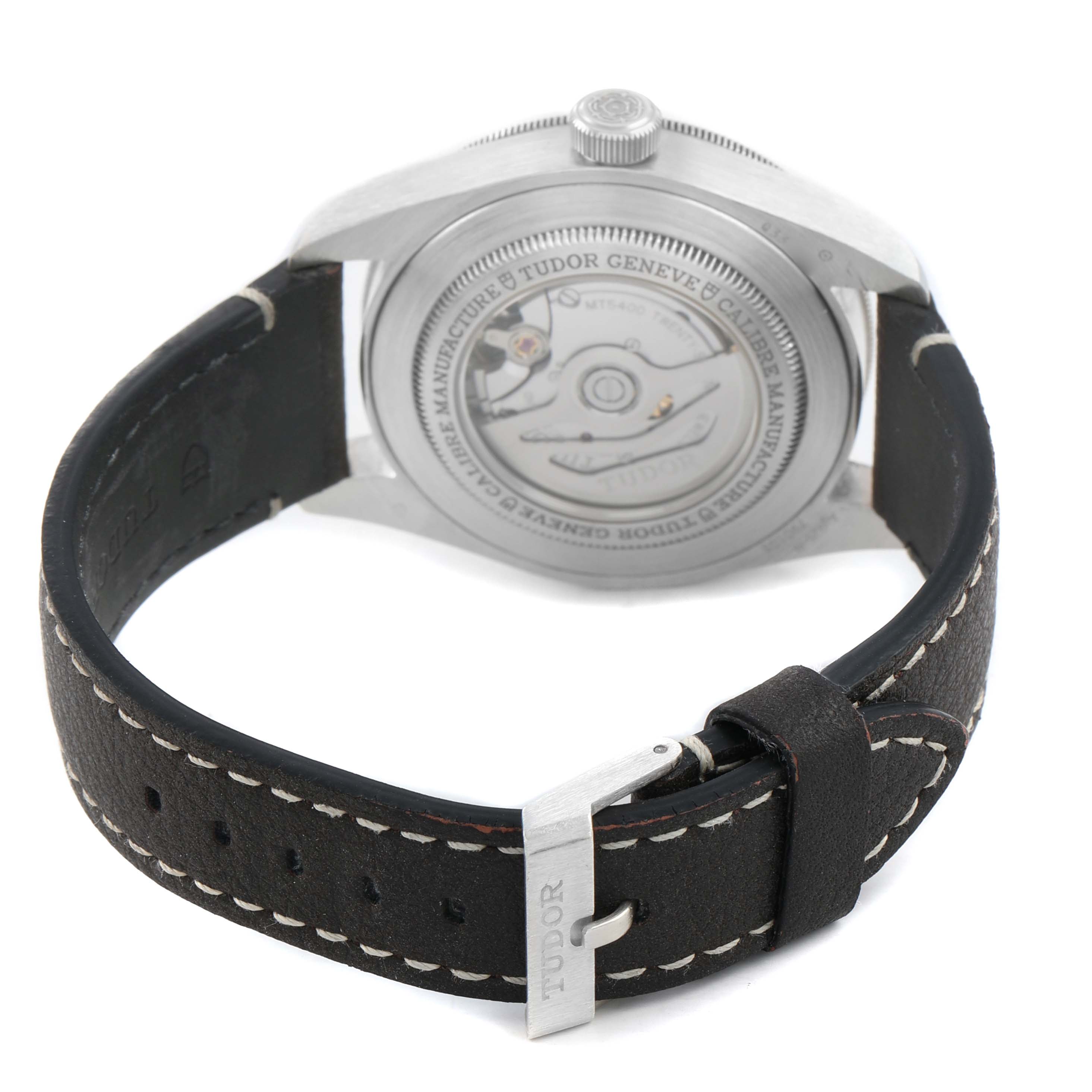 The Tudor Heritage Black Bay 79010 Men's Stainless Steel Grey Dial watch is shown from the back, highlighting the automatic movement and leather strap with buckle.