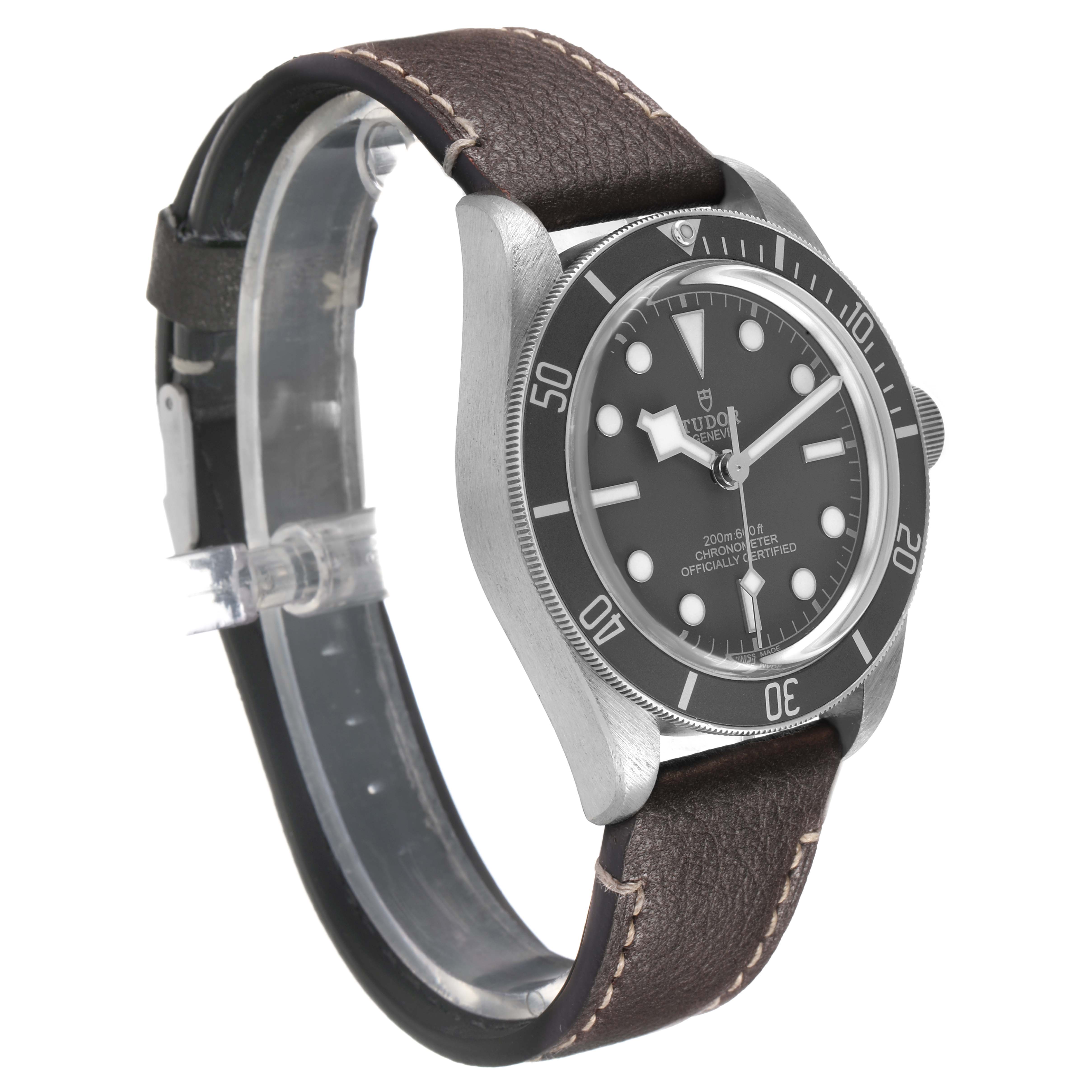 The Tudor Heritage Black Bay 79010 Men's Stainless Steel Grey Dial watch is shown from a front angle, highlighting its black dial, bezel, and leather strap.