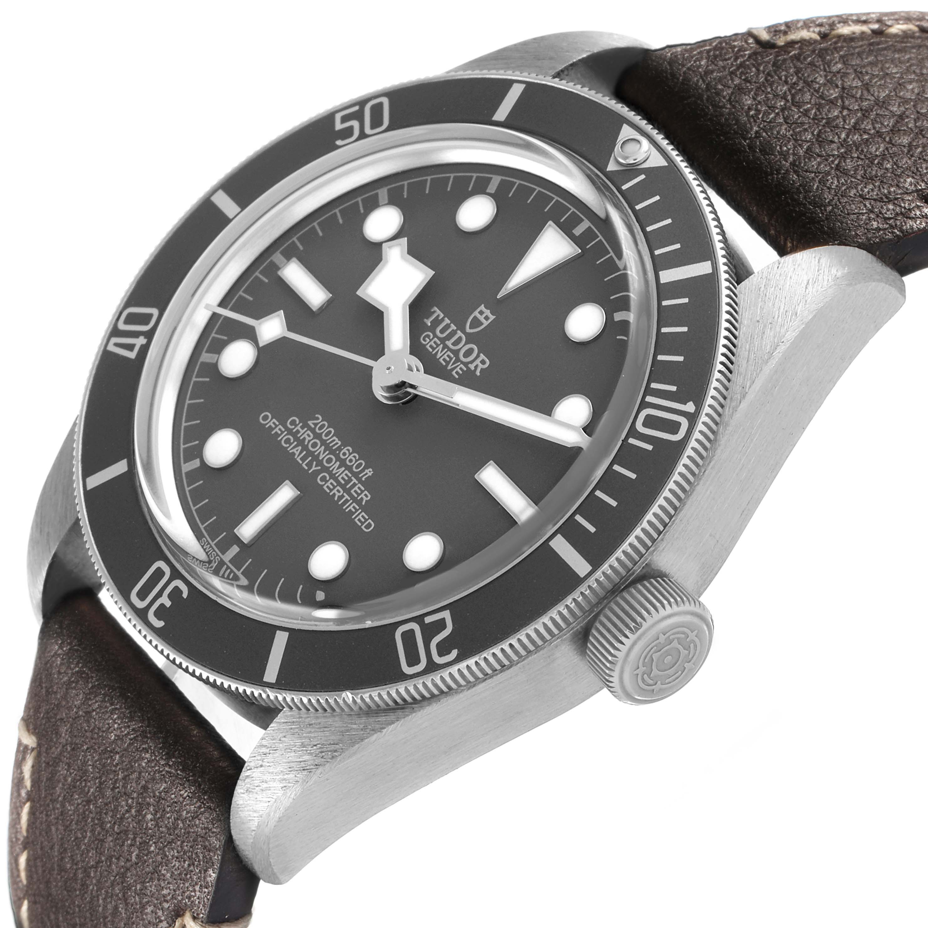 The Tudor Heritage Black Bay 79010 Men's Stainless Steel Grey Dial watch is shown from an angled side view, highlighting the dial, bezel, crown, and leather strap.
