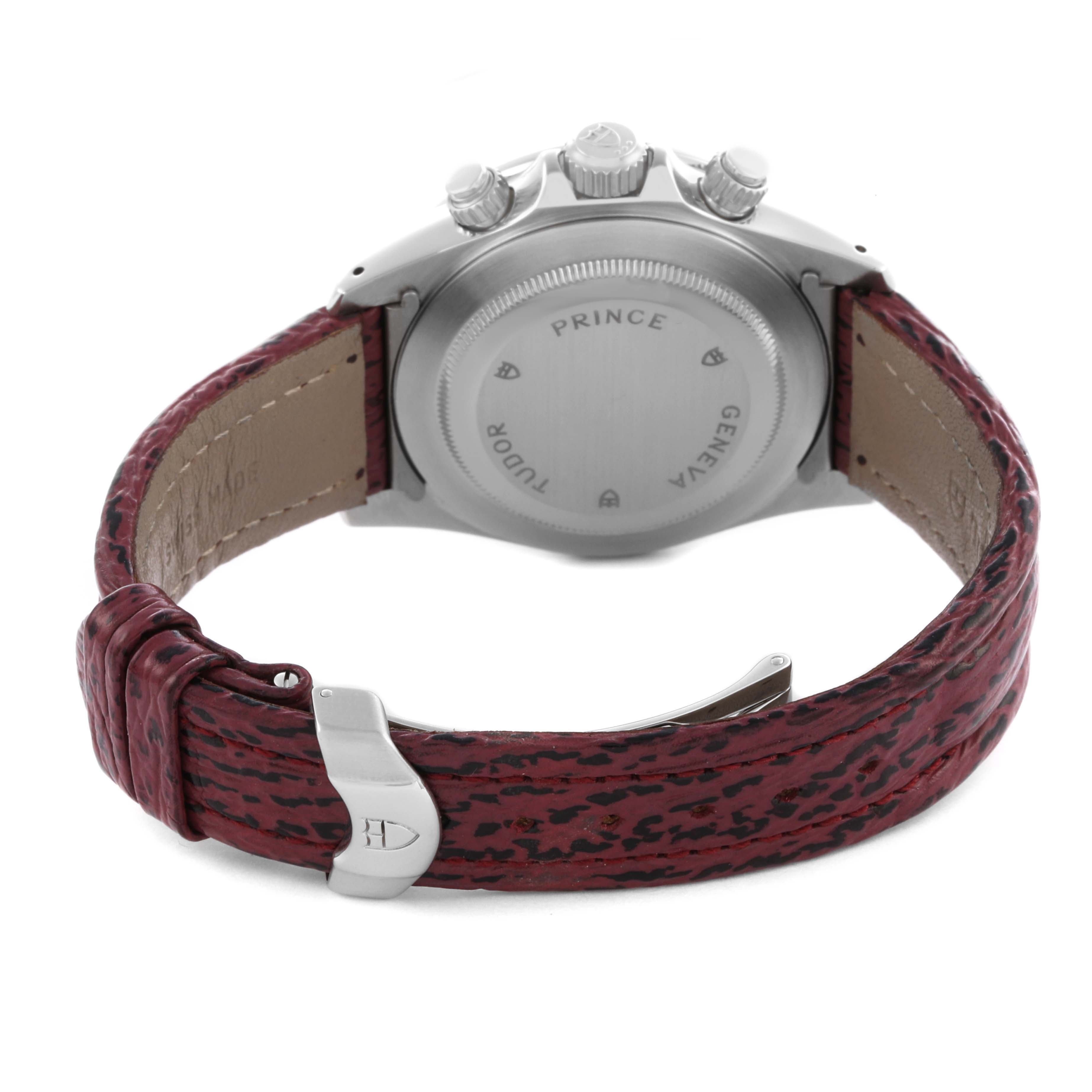 The Tudor Tiger 79280P Men's Stainless Steel Red Dial 79280P Men's Stainless Steel Red Dial watch is shown from the back, highlighting the case back, crown, pushers, and a red leather strap with a buckle.