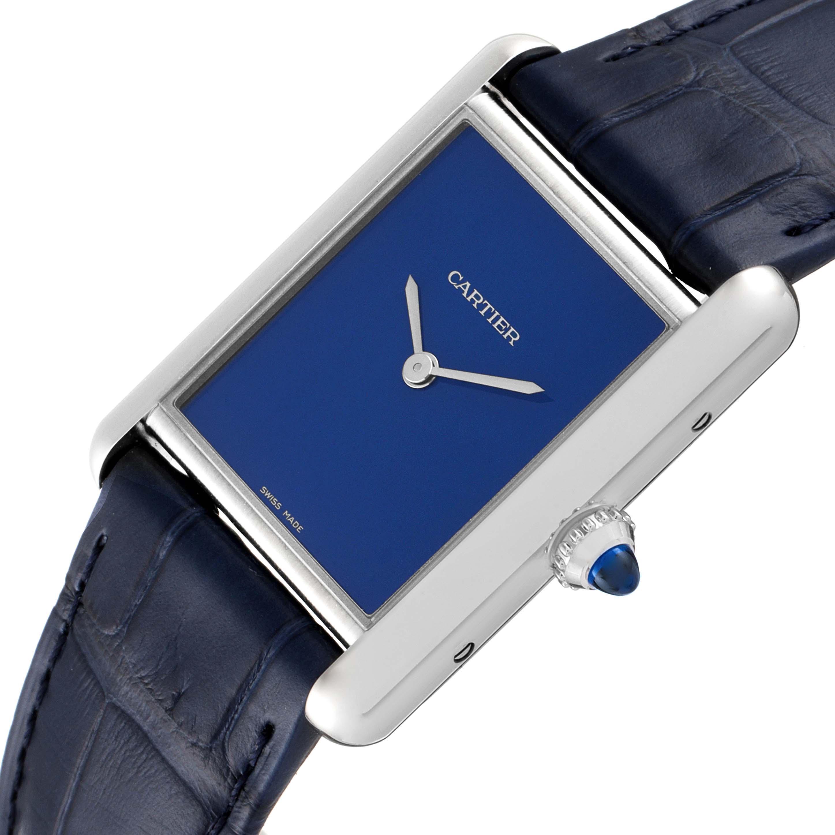 This image shows a close-up angle of the Tank Must model by Cartier, highlighting its blue dial, crown, and leather strap.