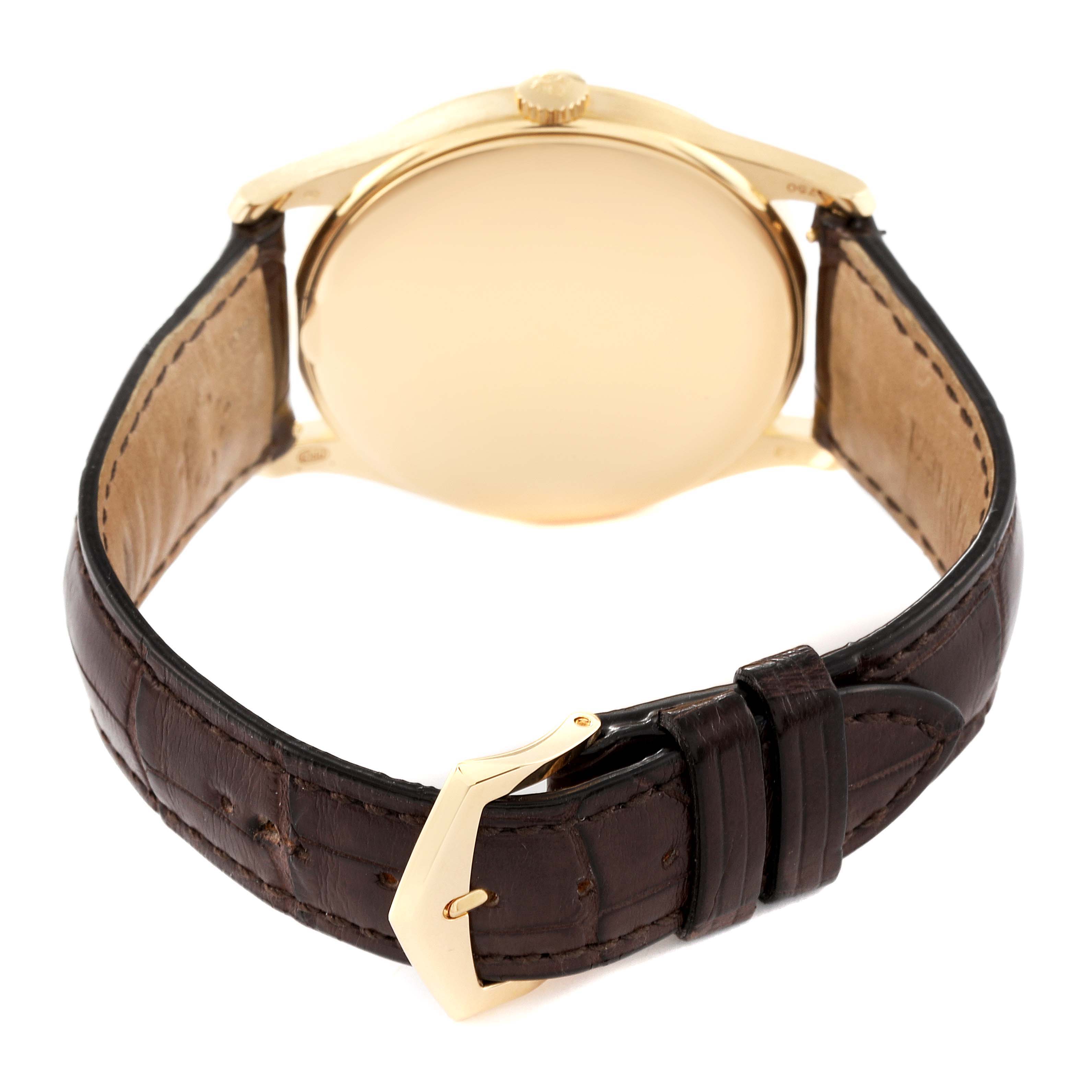 The image shows the back view of a Patek Philippe Calatrava 5196J Men's Yellow Gold Silver Dial 5196J Men's Yellow Gold Silver Dial watch, highlighting the case, crown, and leather strap with a gold buckle.