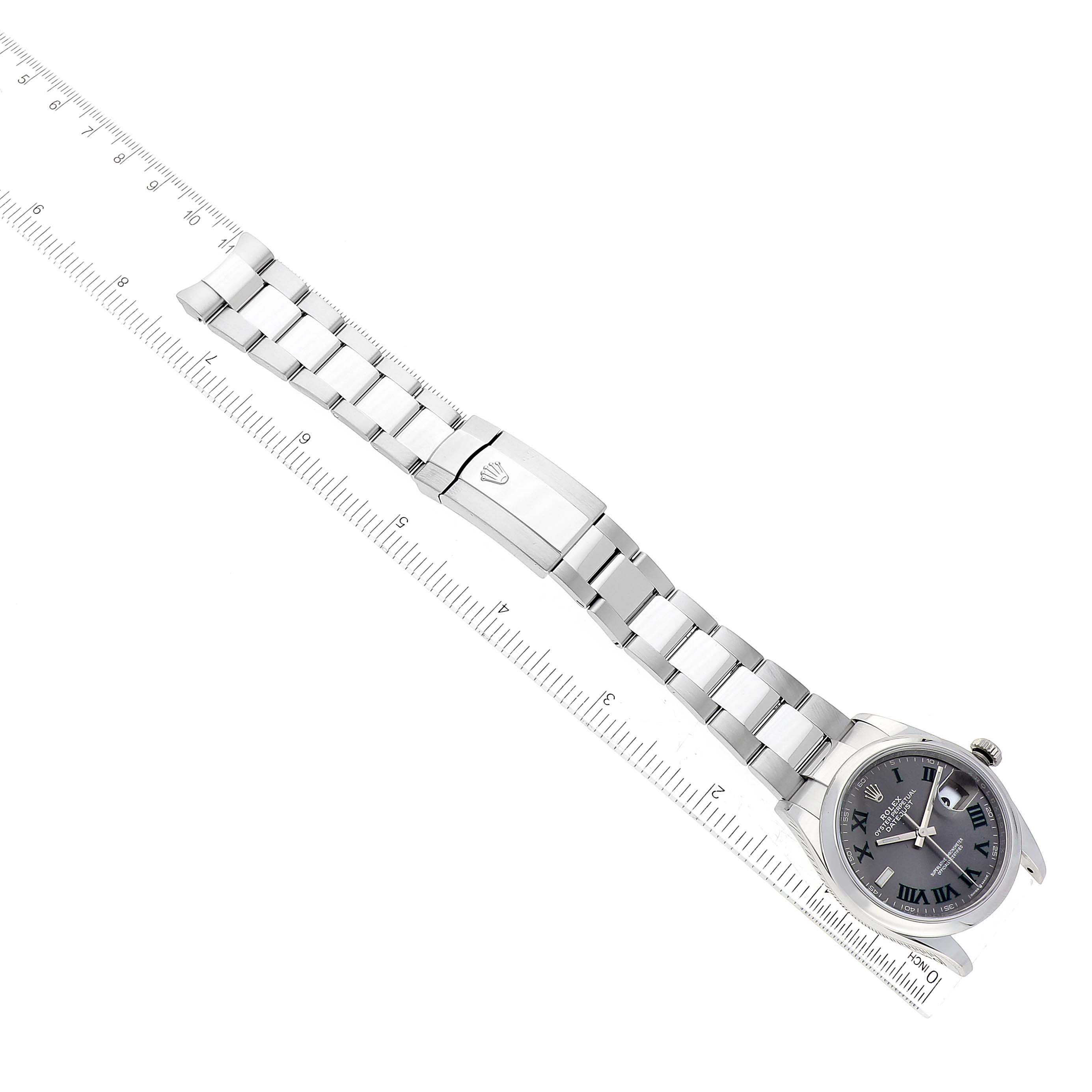 The image shows a Rolex Datejust 126200 Men's Stainless Steel Grey Dial 126200 Men's Stainless Steel Grey Dial watch laid flat, displaying the face and metal bracelet, alongside a measuring ruler.