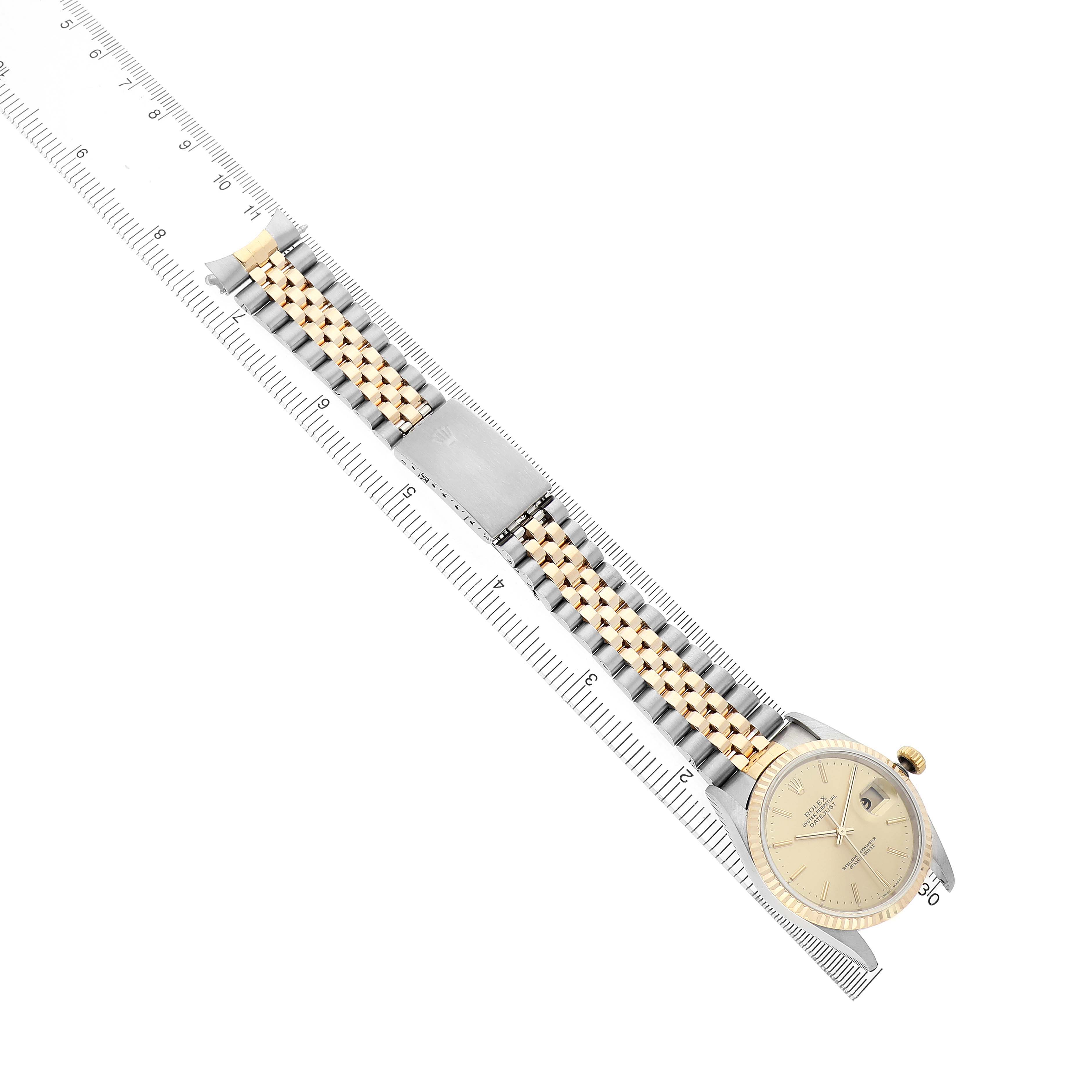 The Rolex Datejust 16233 Men's Steel and Gold (two tone) Champagne Dial watch is shown from a top-down angle, highlighting its face, two-tone bracelet, and clasp, alongside a ruler.