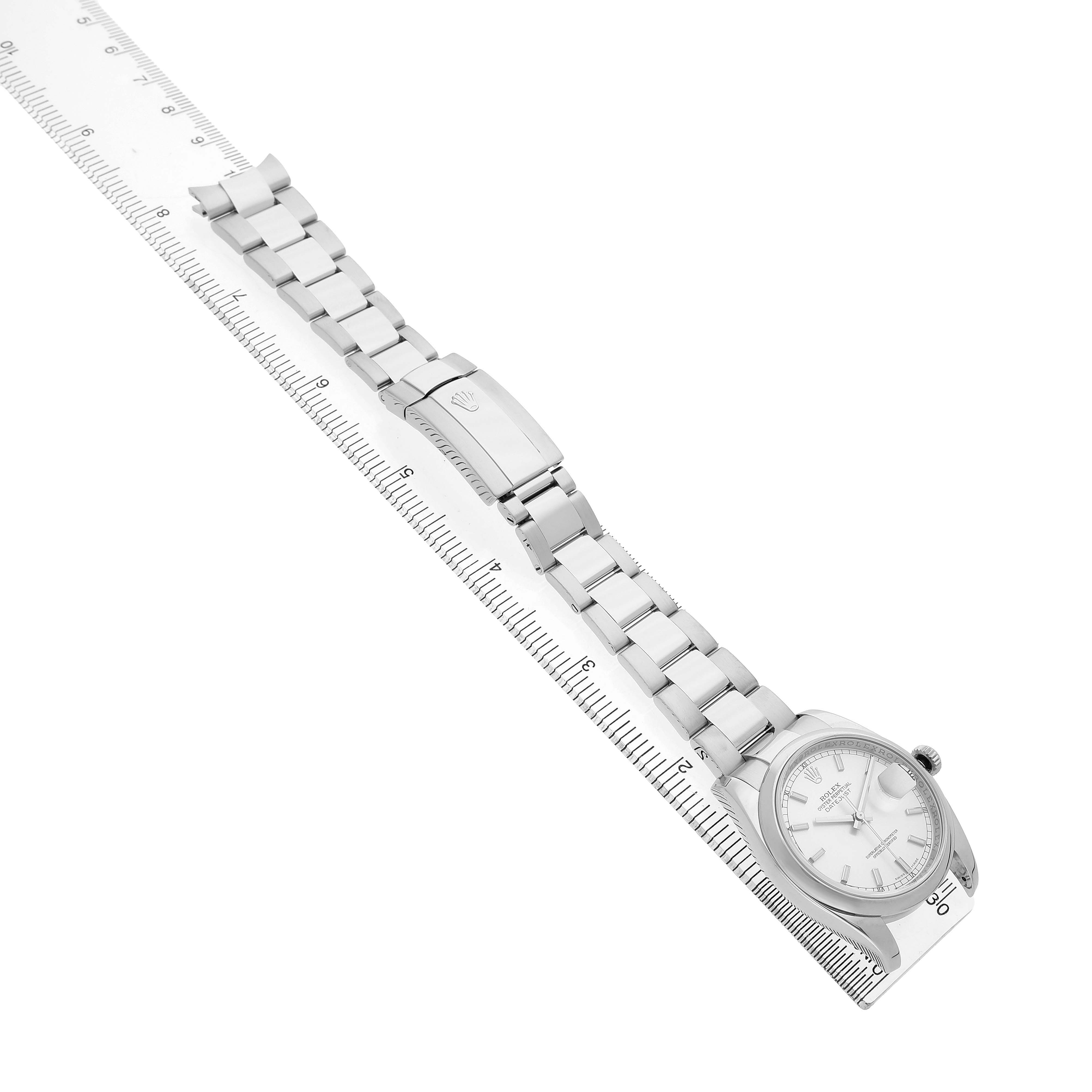 The Rolex Datejust 116200 Men's Stainless Steel Silver Dial watch is shown from an angle displaying its full bracelet and clasp, alongside a ruler for scale.