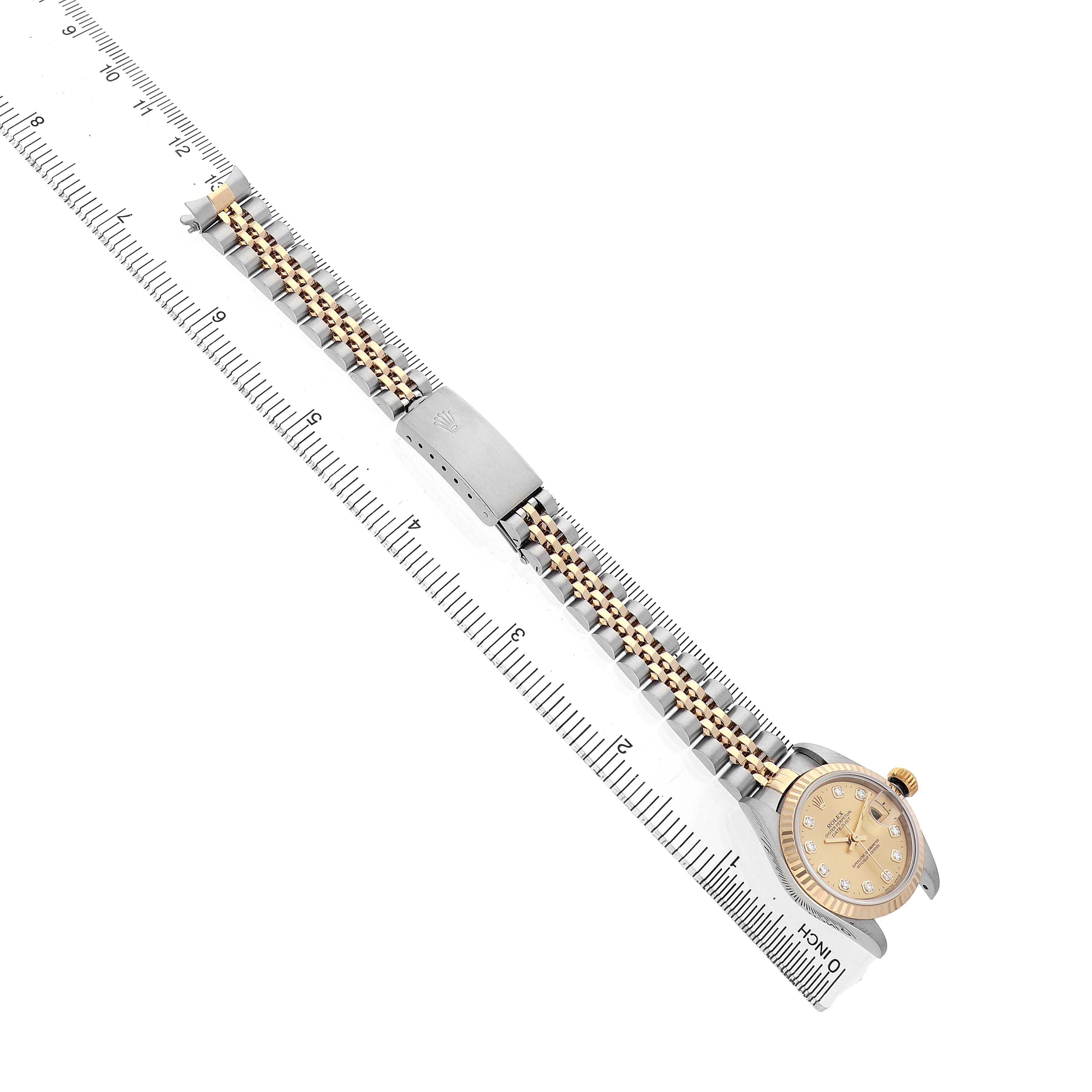 The Rolex Datejust 79173 Women's Steel and Gold (two tone) Champagne Dial watch is shown from a top-down angle, highlighting the bracelet, case, and bezel in a diagonal layout with a ruler.