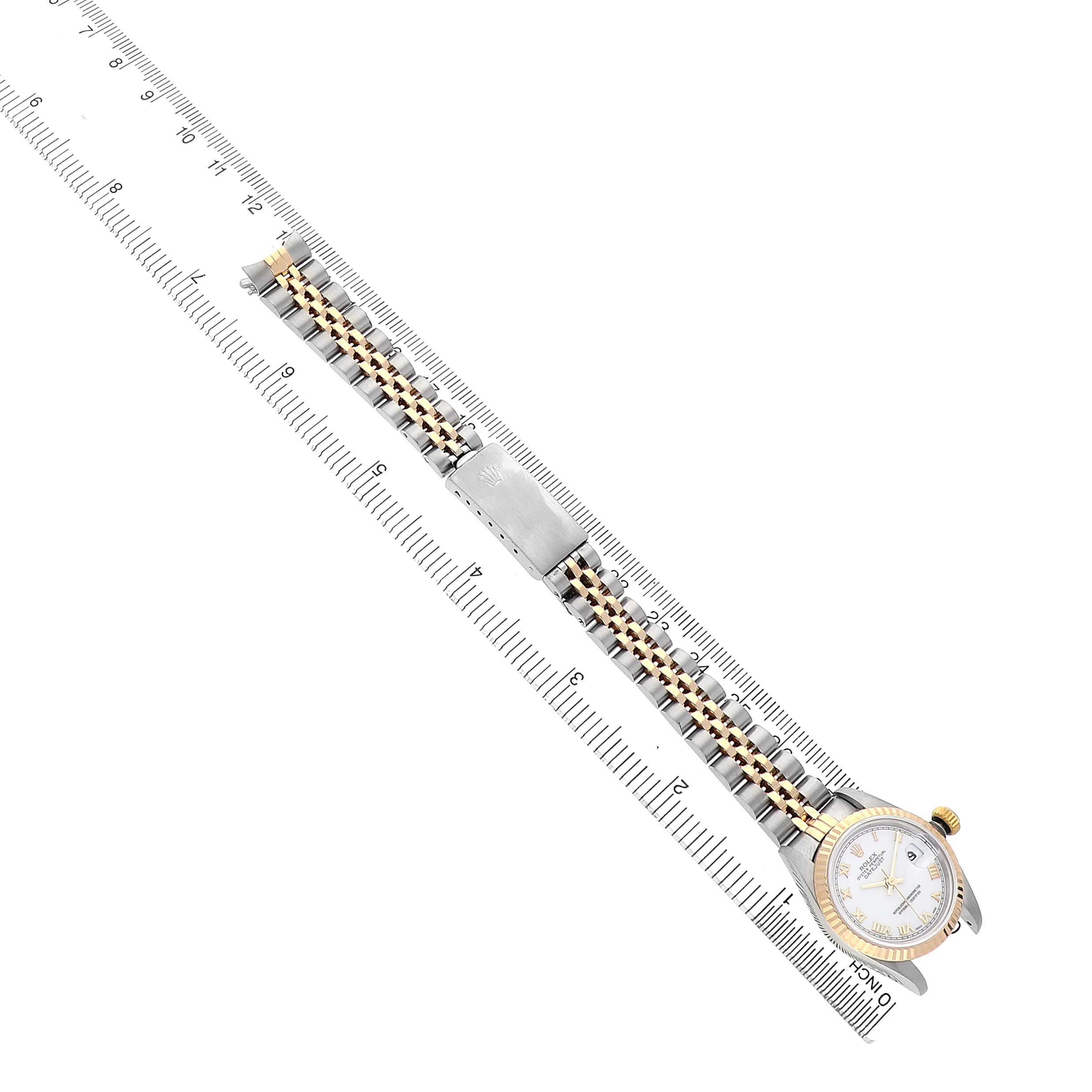 The Rolex Datejust 69173 Women's Steel and Gold (two tone) White Dial watch is shown at a diagonal angle, including the face, bracelet, and clasp, alongside a ruler for scale.