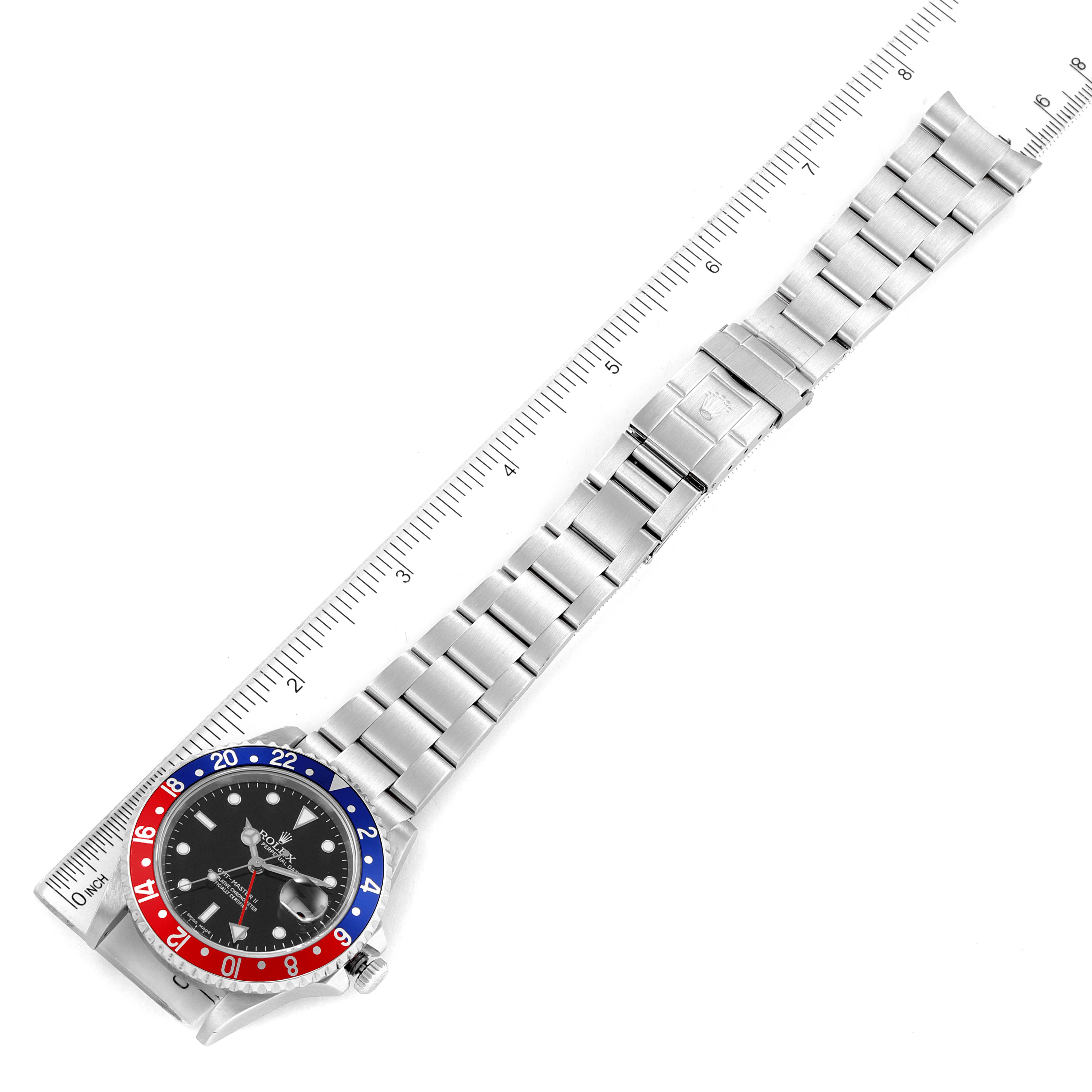 The image shows a Rolex GMT-Master 16710 Men
s Stainless Steel Black Dial 16710 Men
s Stainless Steel Black Dial watch laid flat with its face and full bracelet visible, alongside a ruler for scale.