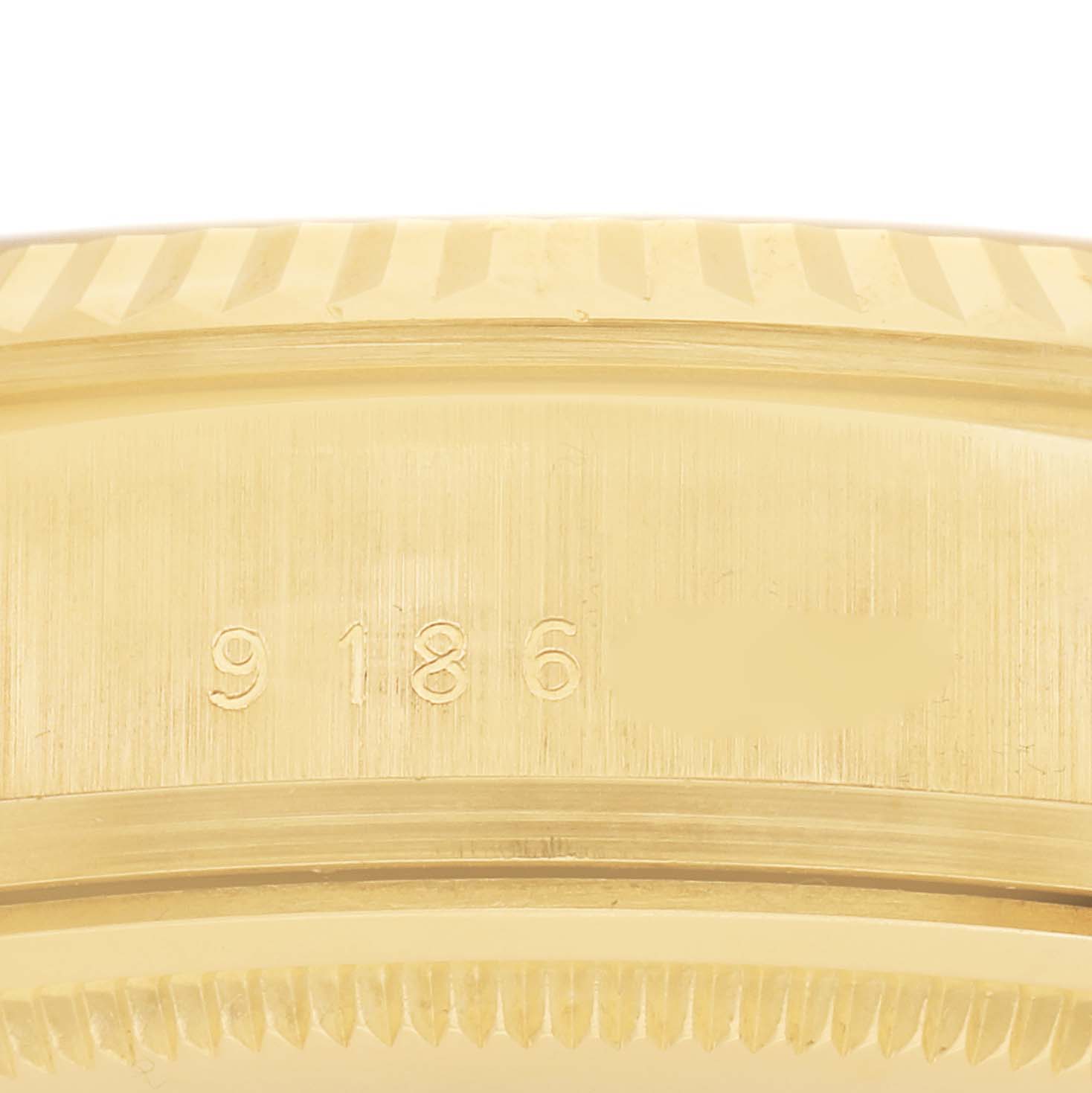 The image shows a close-up of the side of a Rolex President 18038 Men
s Yellow Gold Champagne Dial 18038 Men
s Yellow Gold Champagne Dial watch, focusing on the engraved serial number and fluted bezel.