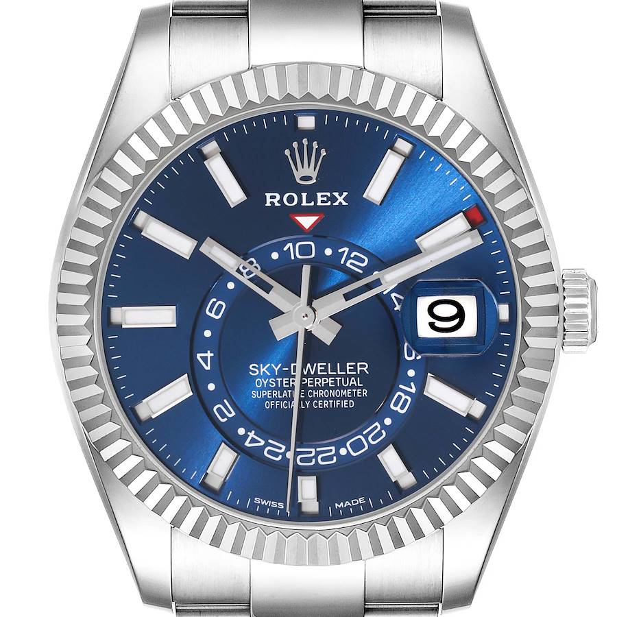 The image shows a front view of the Rolex Sky-Dweller, highlighting the blue dial, fluted bezel, and date window.