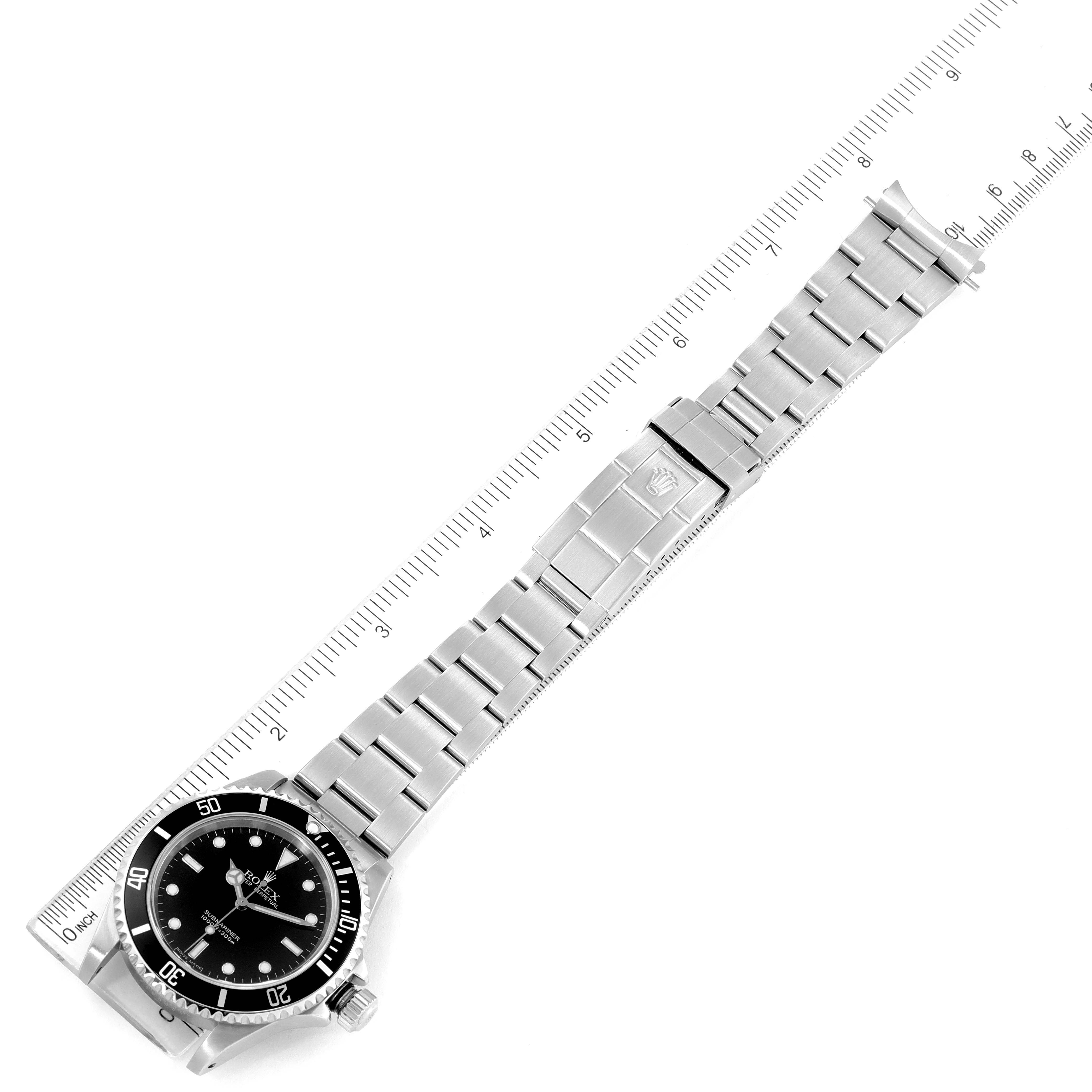 The image shows the Rolex Submariner 14060 Men
s Stainless Steel Black Dial 14060 Men
s Stainless Steel Black Dial watch laid flat with a ruler, displaying the full bracelet and face from a top-down angle.
