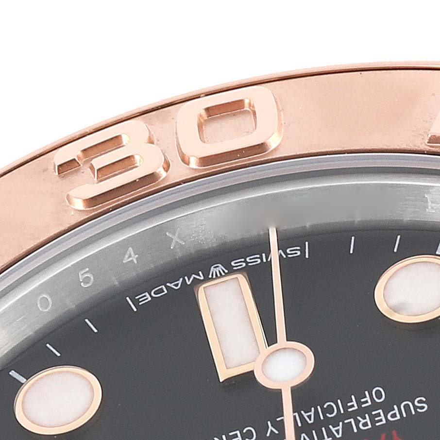 This close-up of the Rolex Yacht-Master 268621 Men
s Steel and Gold (two tone) Black Dial 268621 Men
s Steel and Gold (two tone) Black Dial watch displays part of the bezel, dial, and hands at an angle.