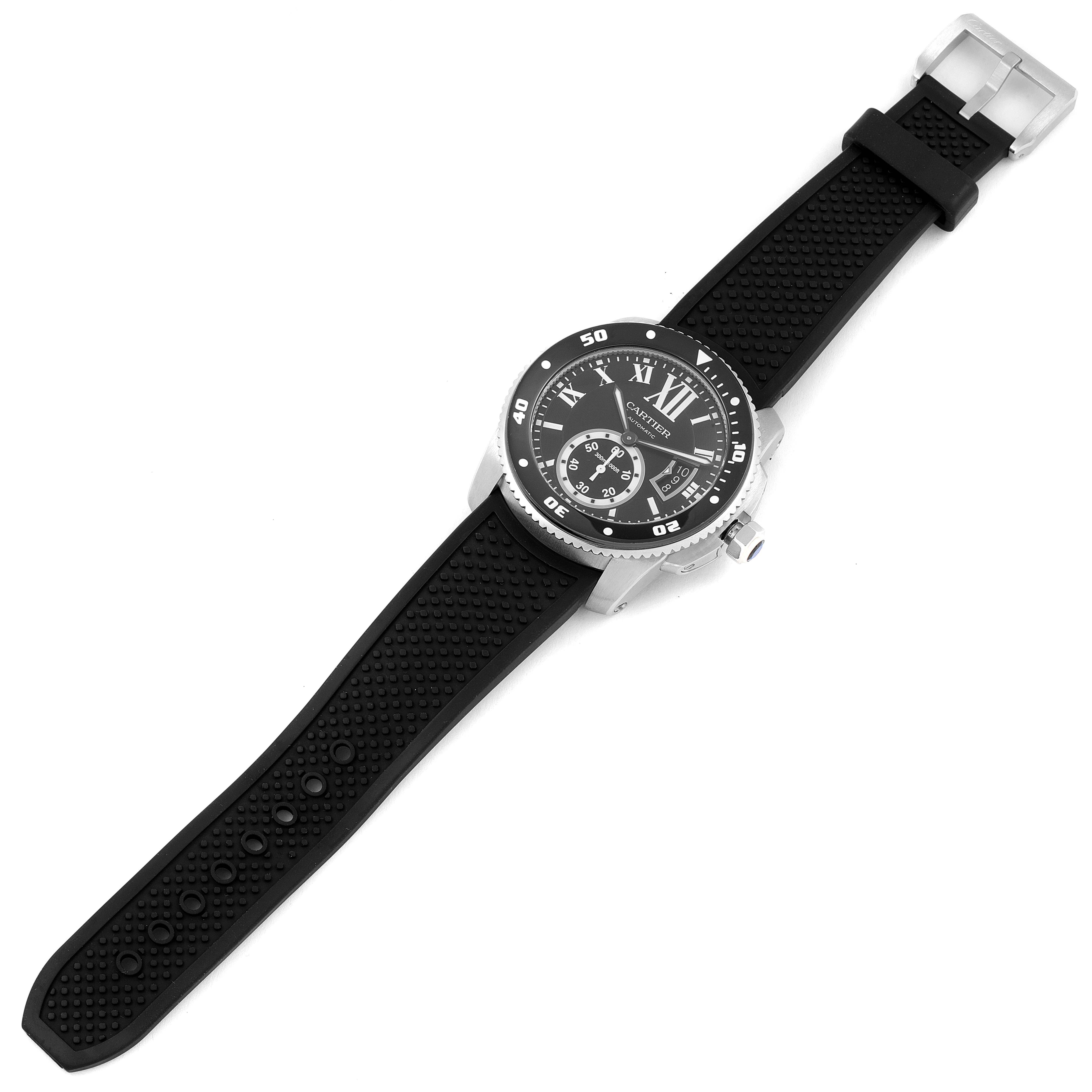 The Calibre de Cartier watch by Cartier is shown from a top-down angle, displaying its face, bezel, and black rubber strap.