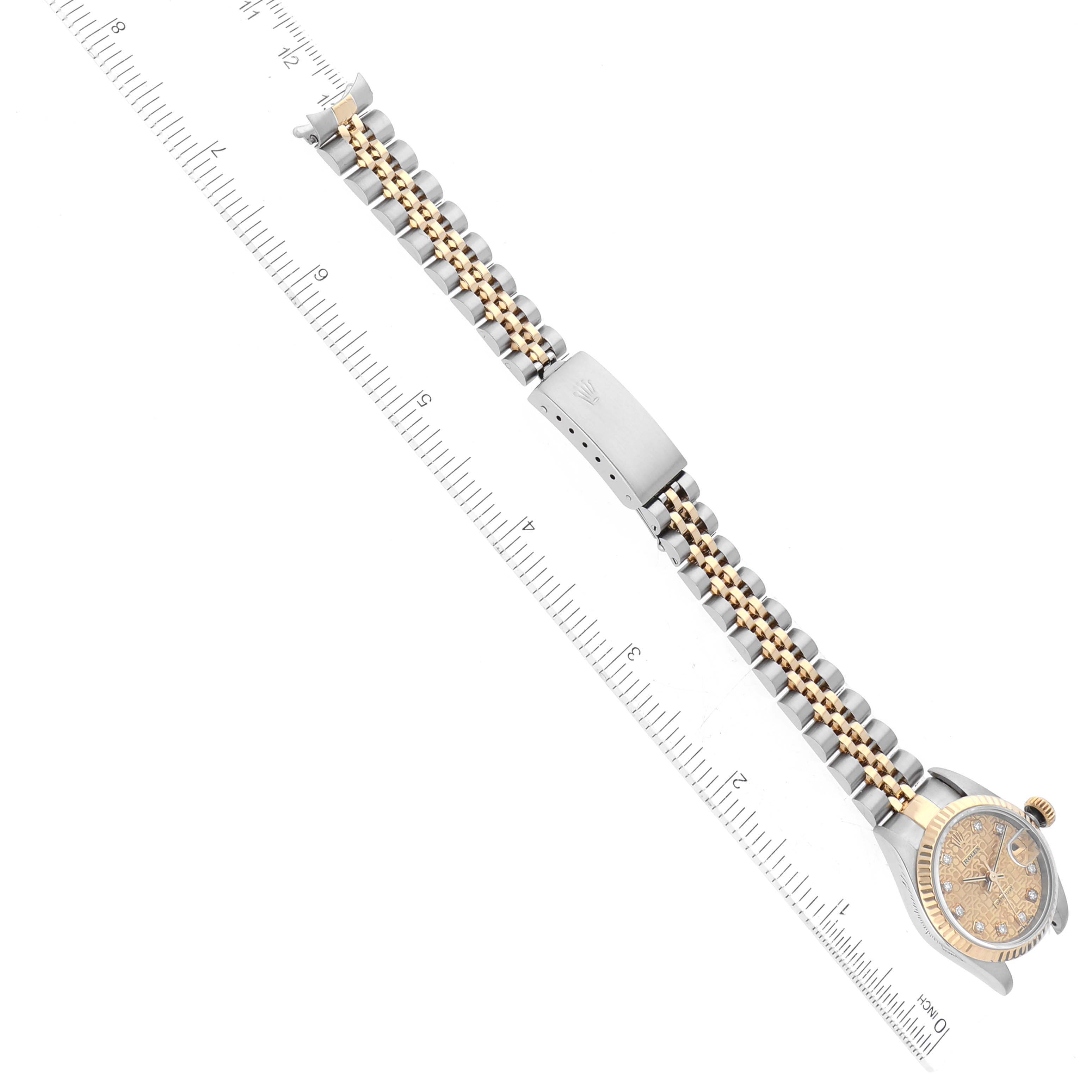 This image shows a top view of a Rolex Datejust 79173G Women's Steel and Gold (two tone) Champagne Dial 79173G Women's Steel and Gold (two tone) Champagne Dial watch with its bracelet extended alongside a ruler.