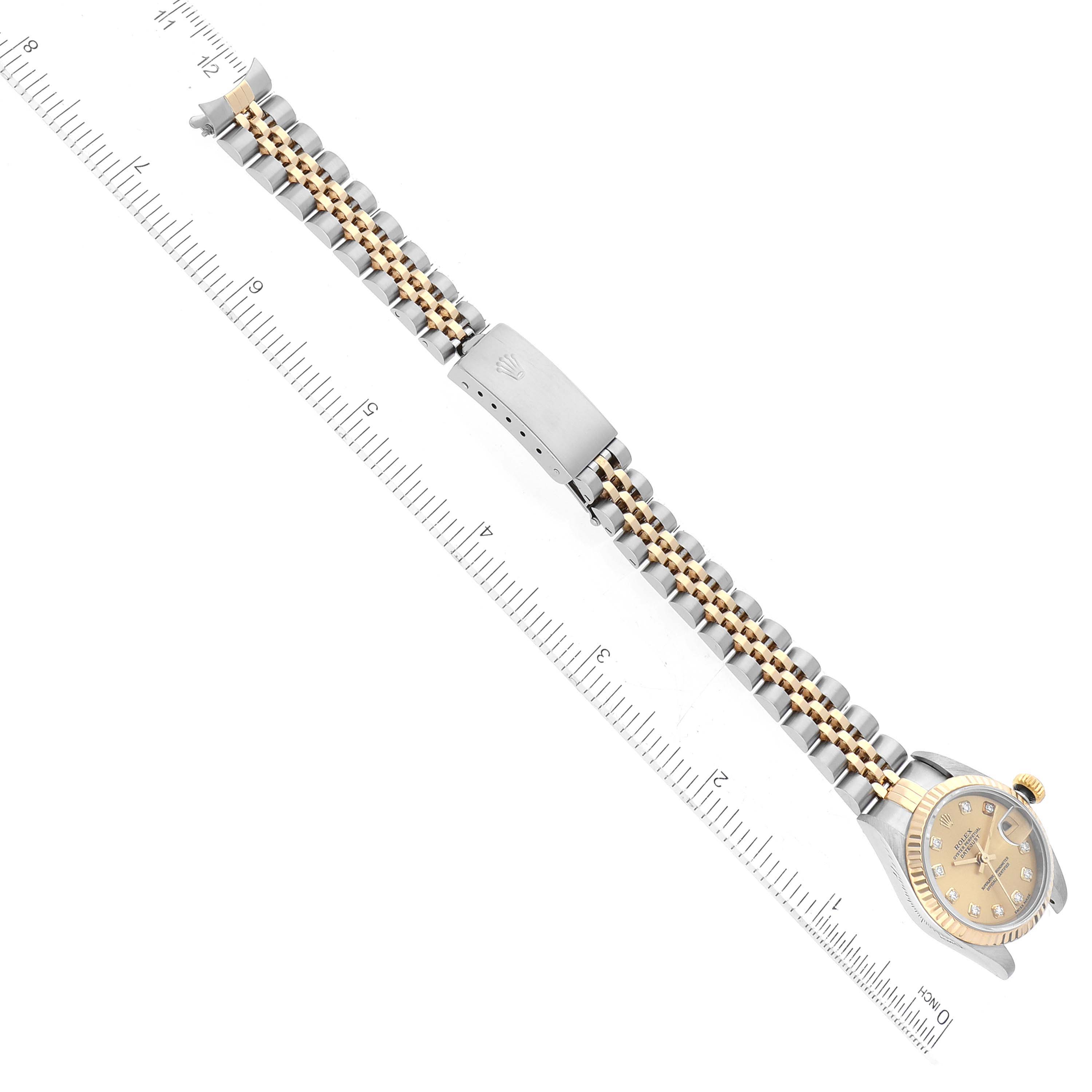 The image shows a top view of a Rolex Datejust 79173G Women's Steel and Gold (two tone) Champagne Dial 79173G Women's Steel and Gold (two tone) Champagne Dial watch laid flat, revealing the face, bracelet, clasp, and a ruler beside it.