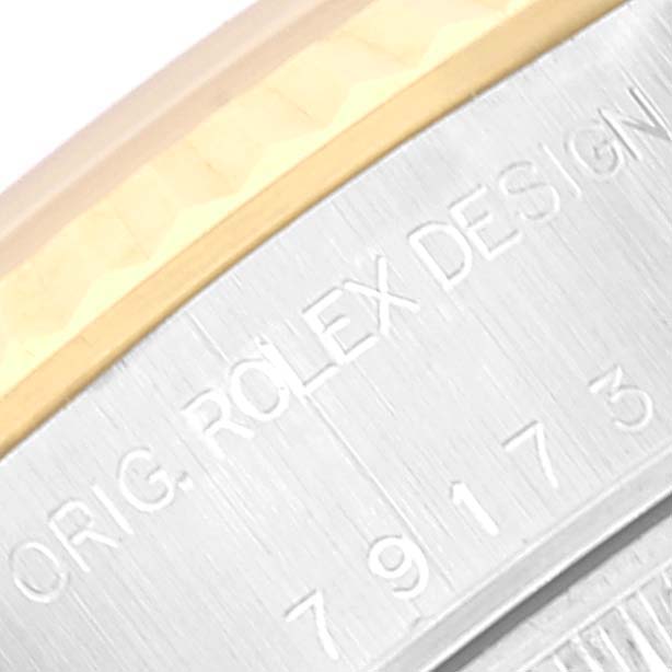 This image shows a close-up of the side of a Rolex Datejust 79173 Women's Steel and Gold (two tone) Silver Dial 79173 Women's Steel and Gold (two tone) Silver Dial watch with parts of the bezel and engraved text visible.