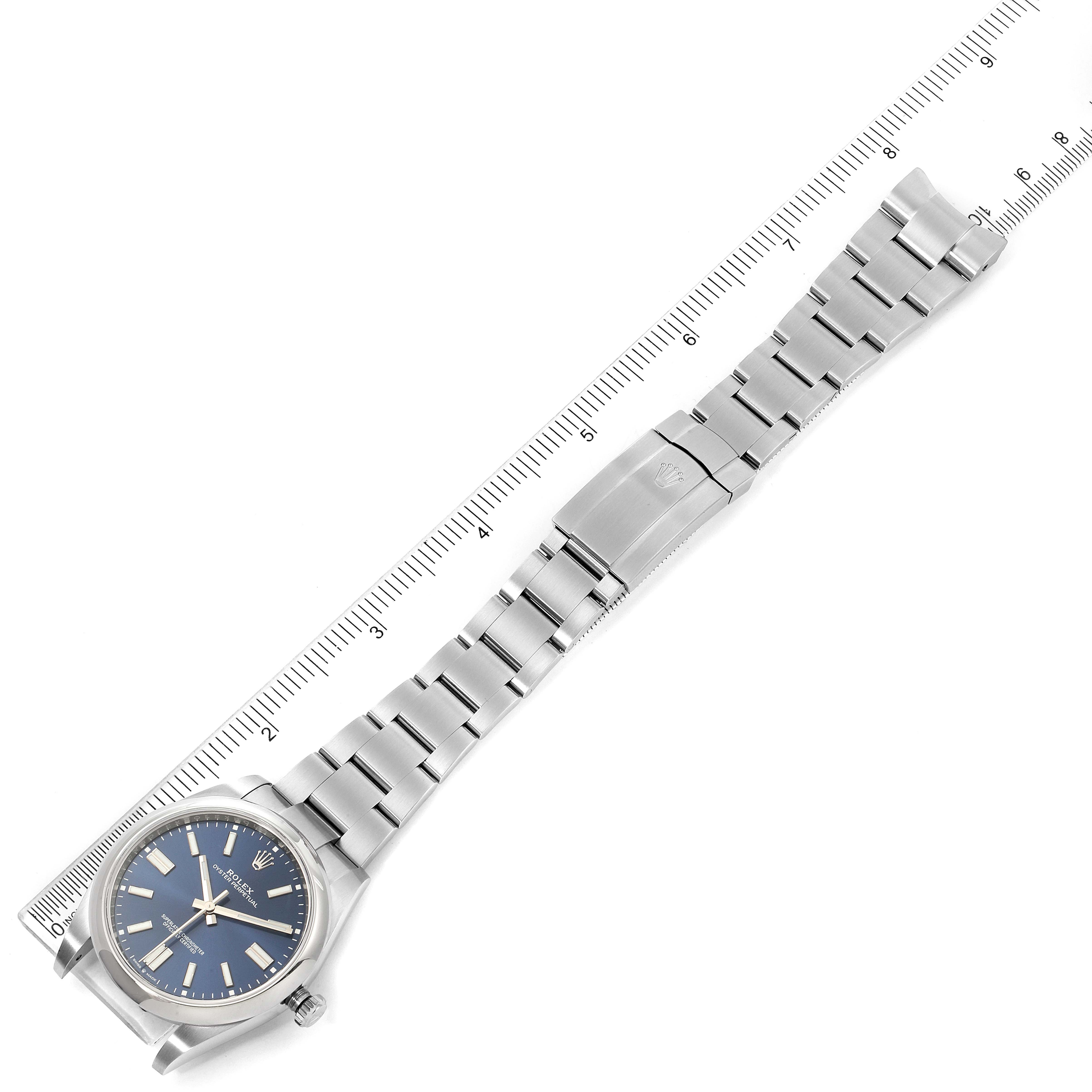 The image shows a Rolex Oyster Perpetual 124300 Men's Stainless Steel Blue Dial 124300 Men's Stainless Steel Blue Dial watch laid flat with its bracelet extended, aligned with a ruler for measurement.