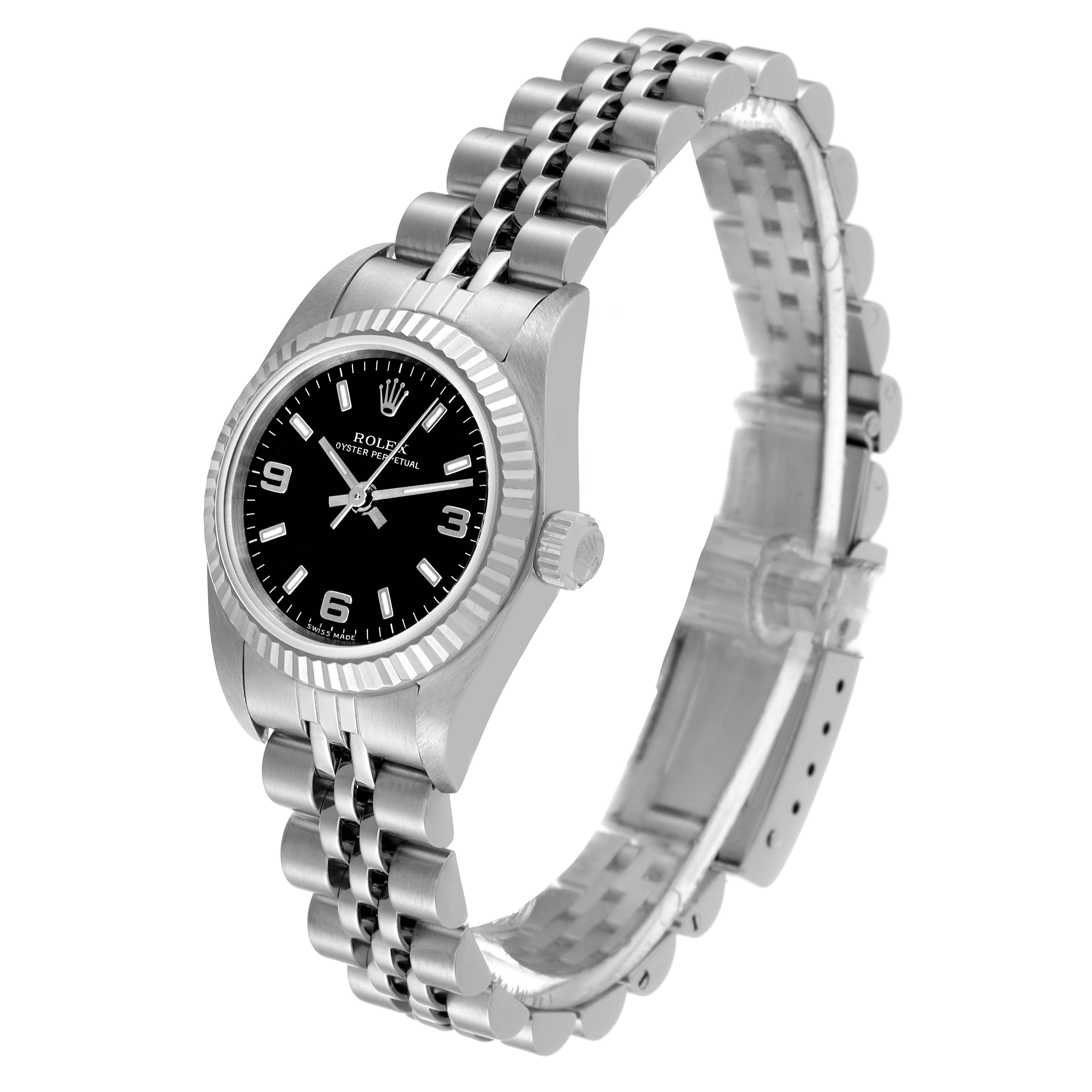The image displays a Rolex Oyster Perpetual 76094 Women's Stainless Steel Black Dial 76094 Women's Stainless Steel Black Dial watch at a slight side angle, showcasing its black dial, fluted bezel, and Jubilee bracelet.