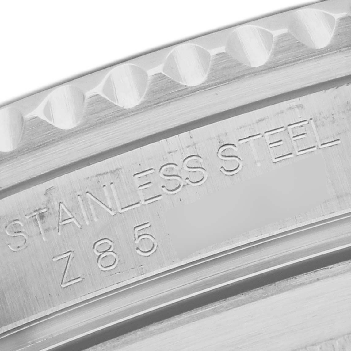 Close-up of the edge of a Rolex Submariner 16610 Men
s Stainless Steel Black Dial 16610 Men
s Stainless Steel Black Dial
s stainless steel case, showing the engraved "STAINLESS STEEL" text and a portion of the bezel.