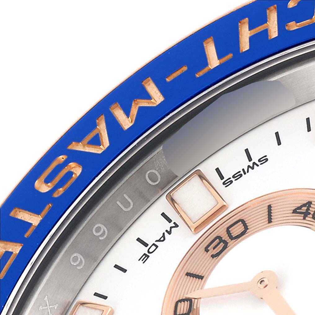 A close-up of the Rolex Yacht-Master 116681 Men's Steel and Gold (two tone) White Dial 116681 Men's Steel and Gold (two tone) White Dial watch shows part of the blue bezel, dial, and hour markers.