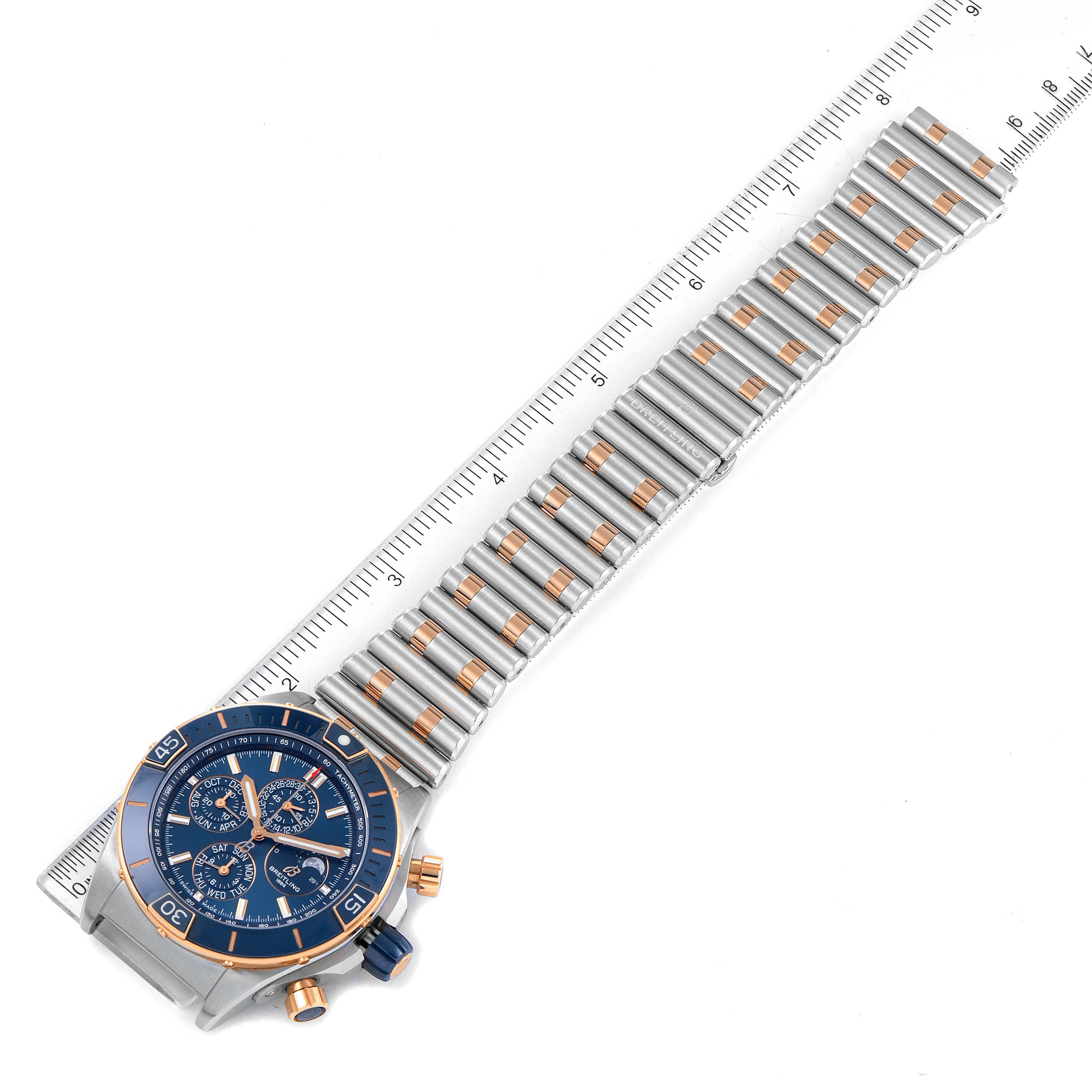 The image shows a top-down view of a Breitling Chronomat U19320161C1U1 Men's Steel and Gold (two tone) Blue Dial U19320161C1U1 Men's Steel and Gold (two tone) Blue Dial watch with its entire band, aligned with a ruler for scale.