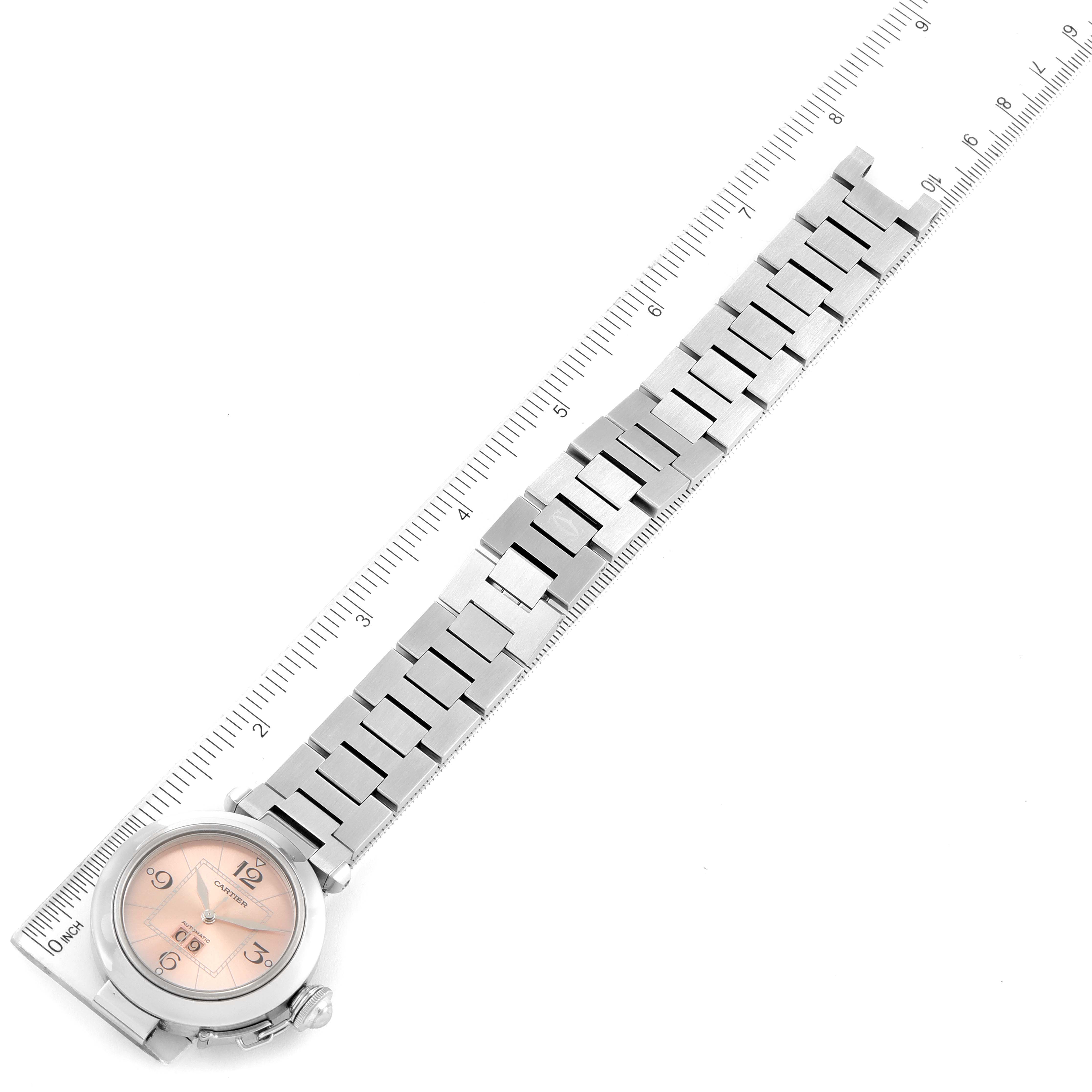 The image shows a top-down view of the Cartier Pasha W31058M7 Women's Stainless Steel Pink Dial W31058M7 Women's Stainless Steel Pink Dial model watch, displaying the face, bracelet, and a measuring ruler.