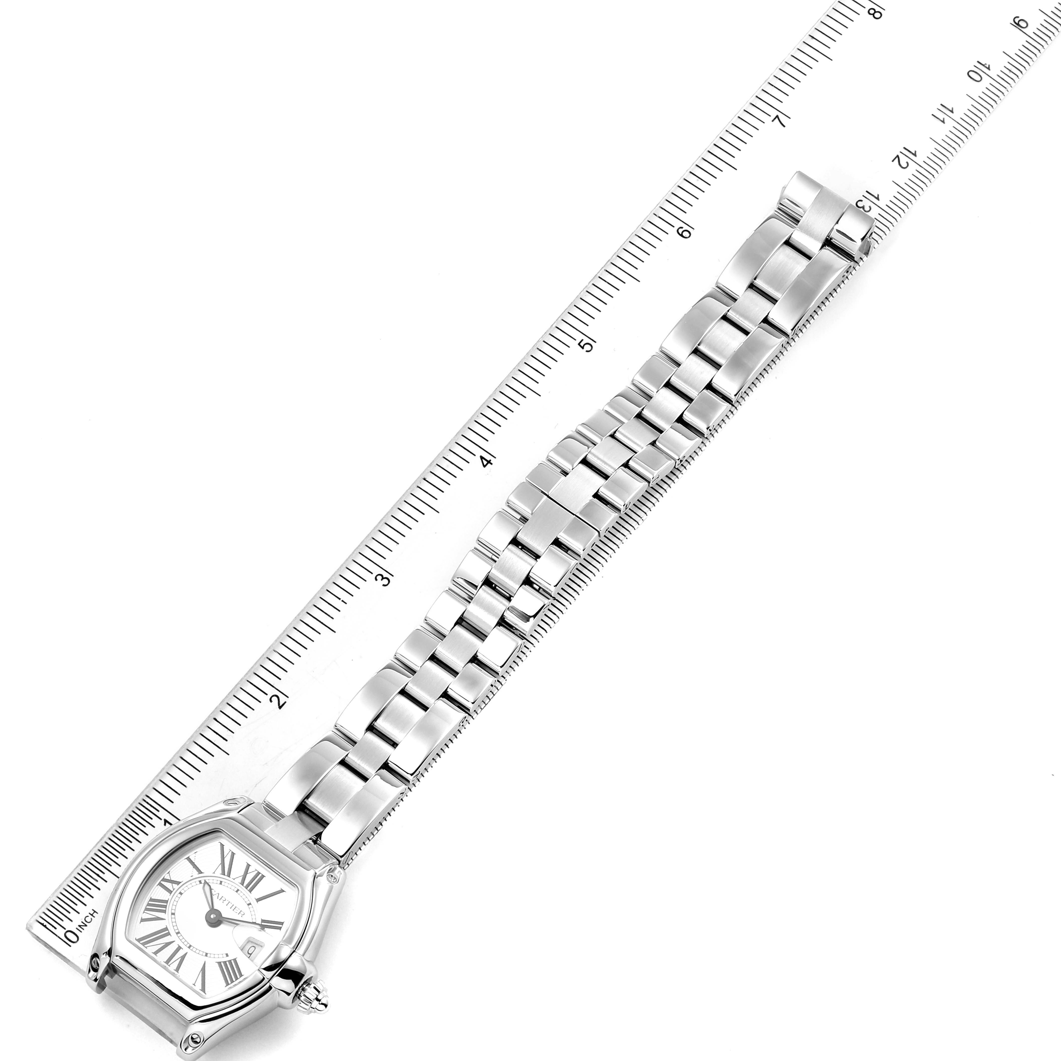The Cartier Roadster W62016V3 Women
s Stainless Steel Silver Dial W62016V3 Women
s Stainless Steel Silver Dial watch is shown from a top-down angle, displaying both the face and the metal bracelet laid along a ruler.