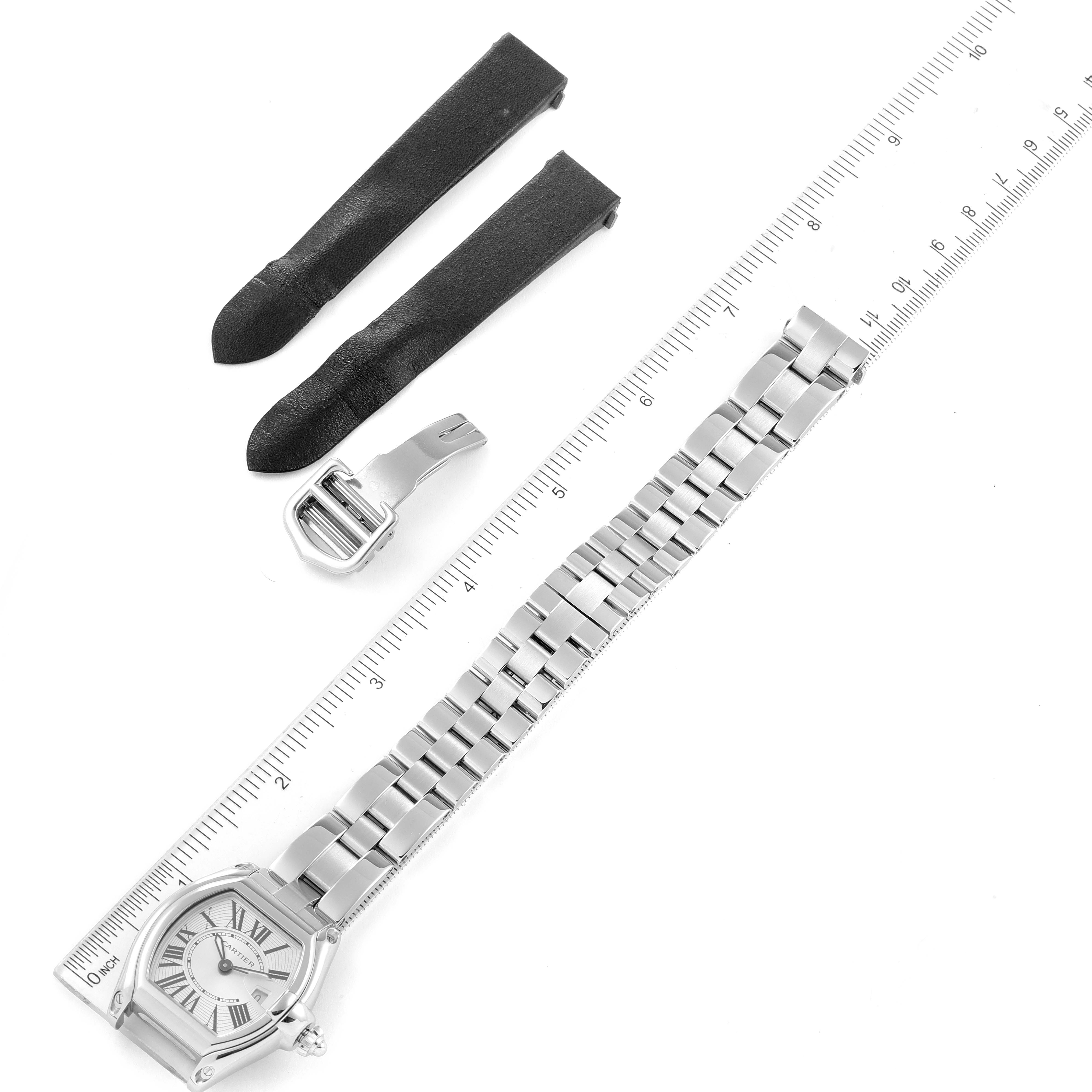 The image shows a Cartier Roadster W62016V3 Women's Stainless Steel Silver Dial W62016V3 Women's Stainless Steel Silver Dial watch, a ruler, two interchangeable straps, and a buckle, taken from a top-down angle.