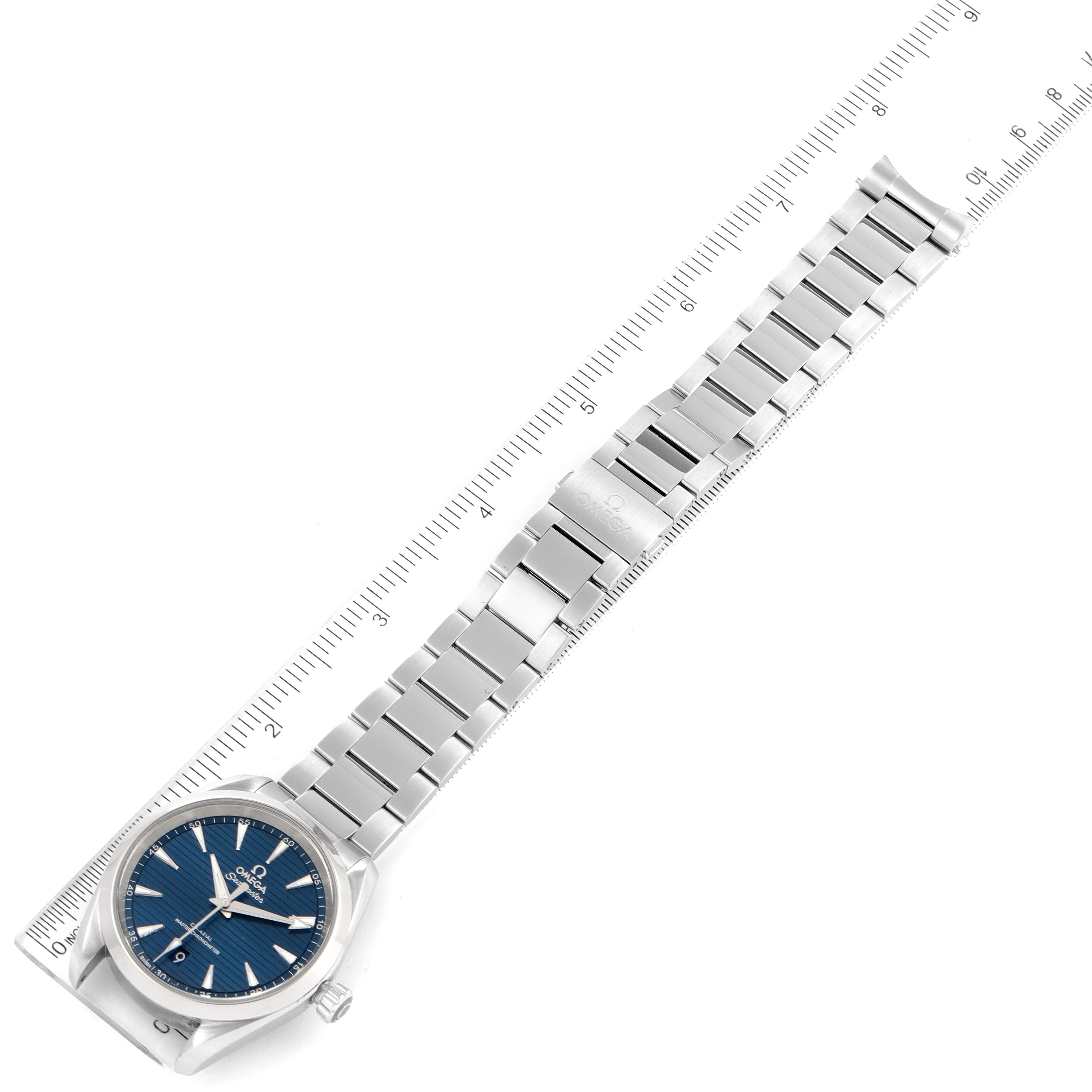 The image shows an Omega Aqua Terra 220.10.38.20.03.001 Men
s Stainless Steel Blue Dial 220.10.38.20.03.001 Men
s Stainless Steel Blue Dial watch laid flat, angled slightly with its stainless steel bracelet extended and aligned with a ruler.